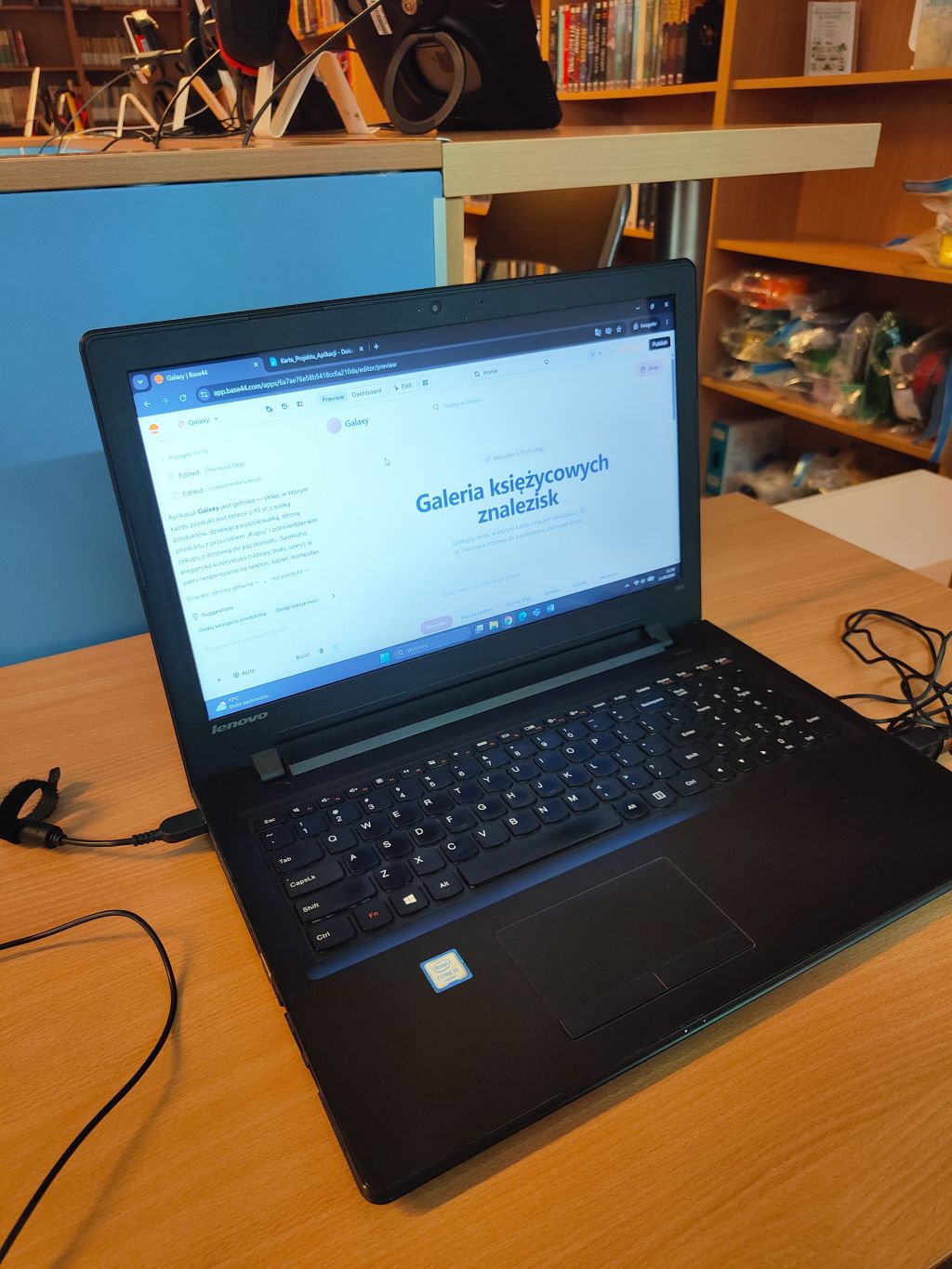 Czarne stanowisko komputerowe z laptopem Lenovo wyświetlającym stronę o nazwie „Galeria księżycowych znalezisk”.