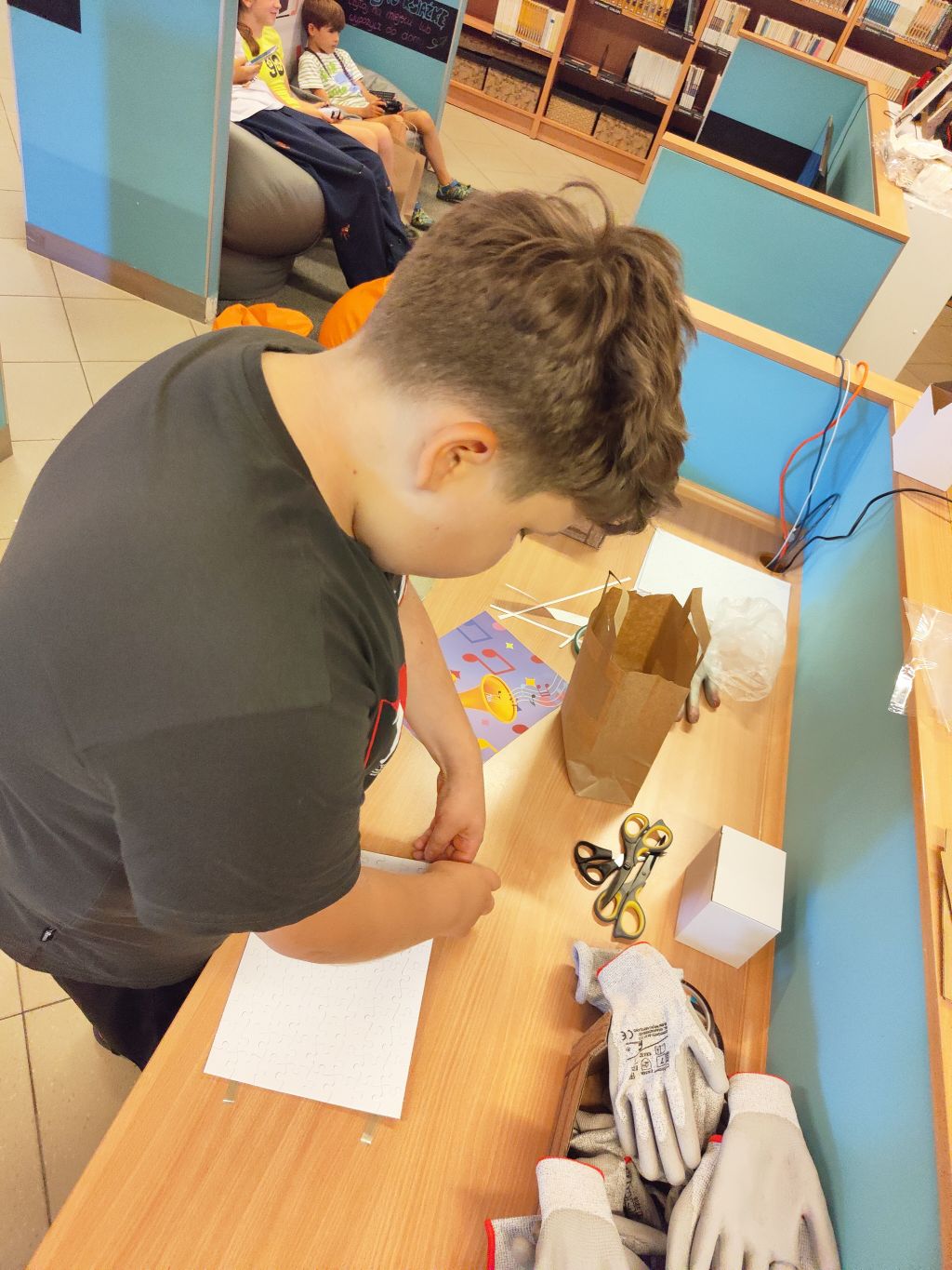 Chłopak przy stoku roboczym dopasowuje elementy białych puzzli, przygotowując je do nadruku.