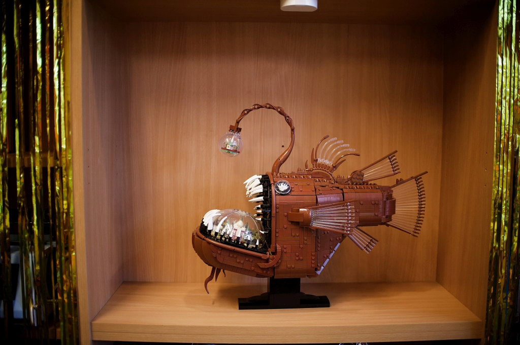 Model fantastycznej ryby z klocków LEGO ustawiony na drewnianej półce.