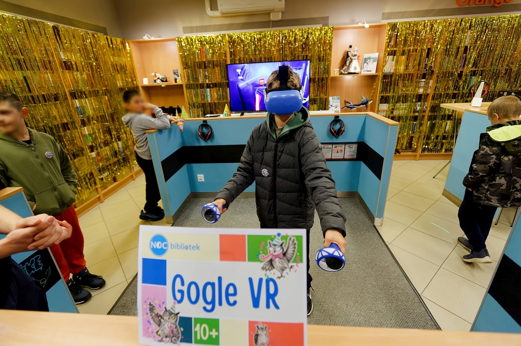 Chłopiec korzysta z gogli VR i kontrolerów w Dziale dla Młodzieży NASTKA.