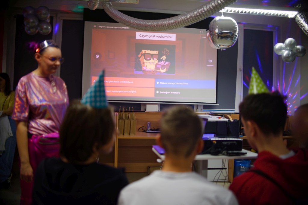 Uczestnicy odpowiadają na pytania quizu Kahoot wyświetlane na dużym ekranie.