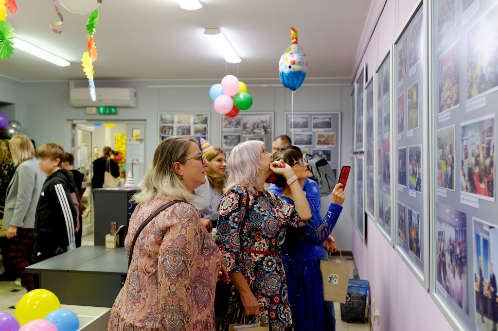 Kobiety oglądają wystawę archiwalnych fotografii z historii biblioteki.