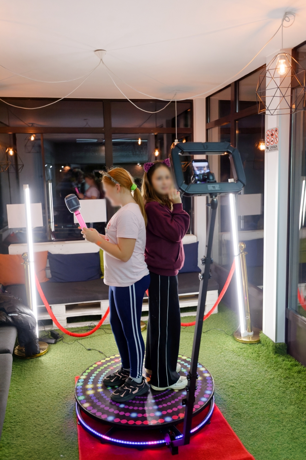 Dwie dziewczynki pozują na obrotowej platformie fotobudki 360.