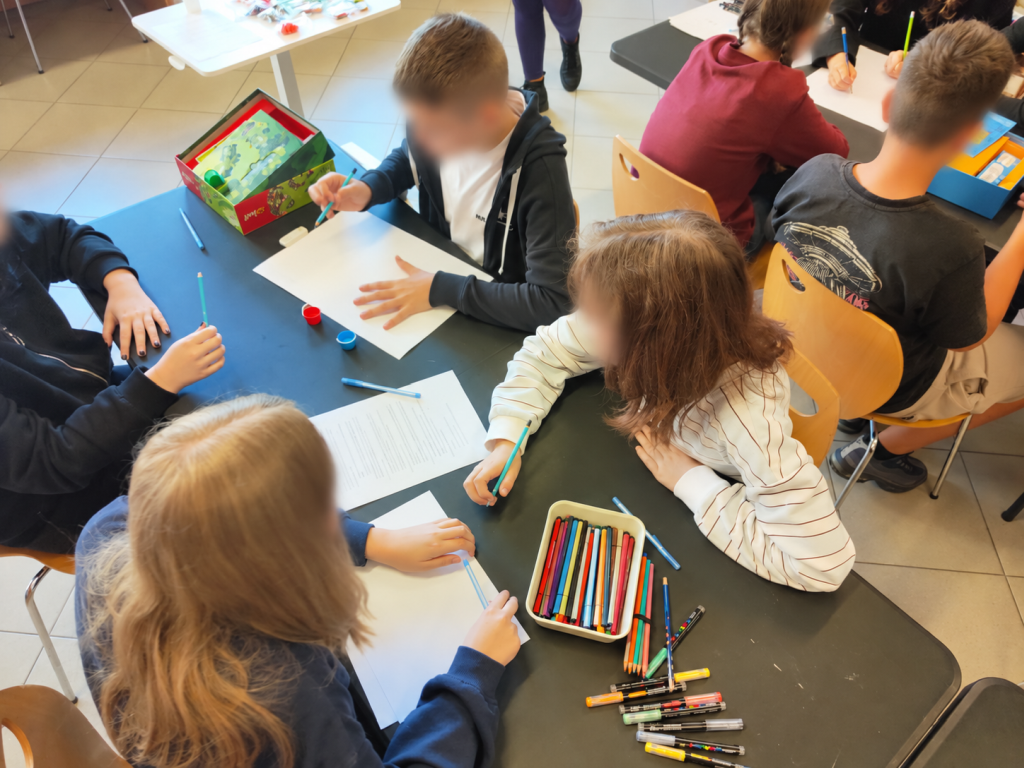 Nastolatki rysują i przygotowują elementy gry przy stole.