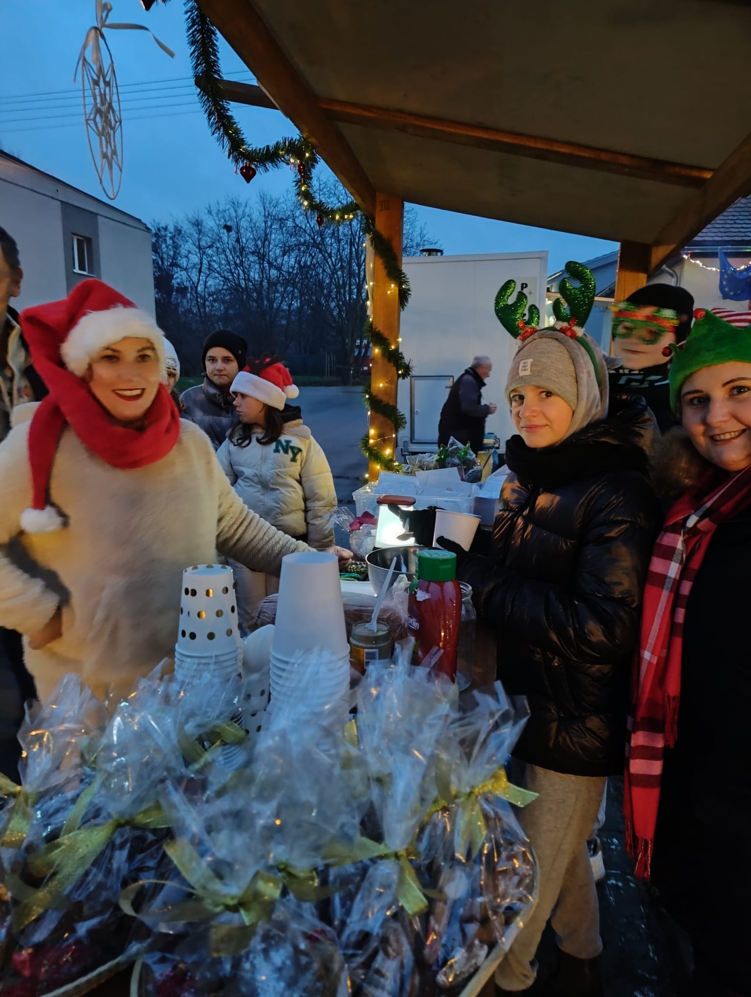 Osoby przy stoisku świątecznym na jarmarku.