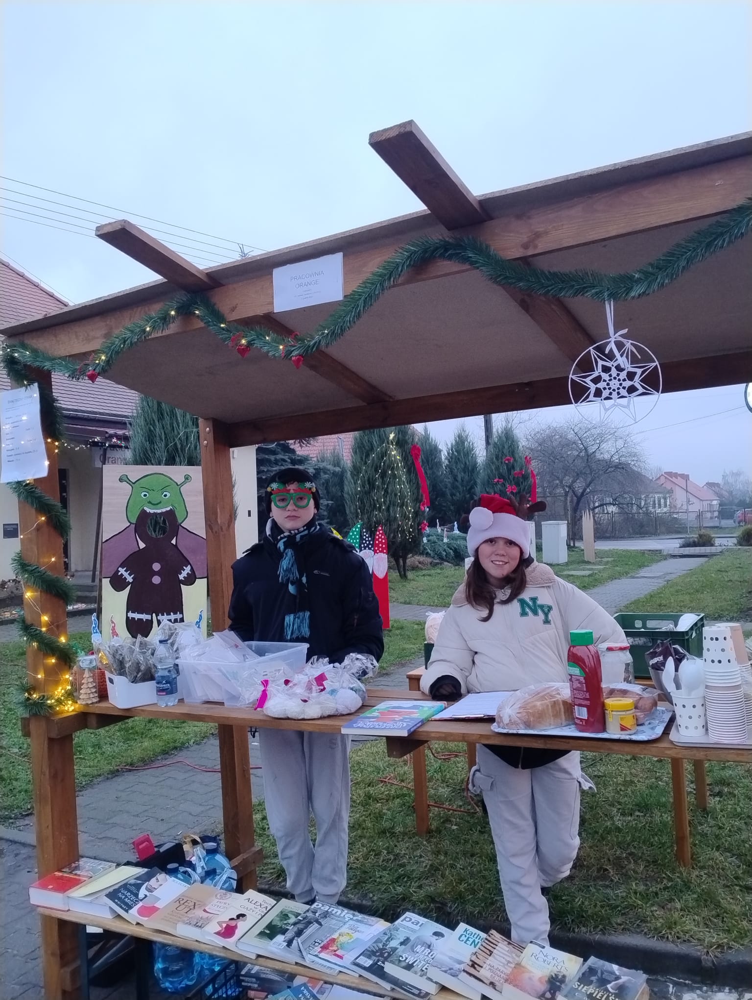 Dwie osoby stojące przy stoisku świątecznym.