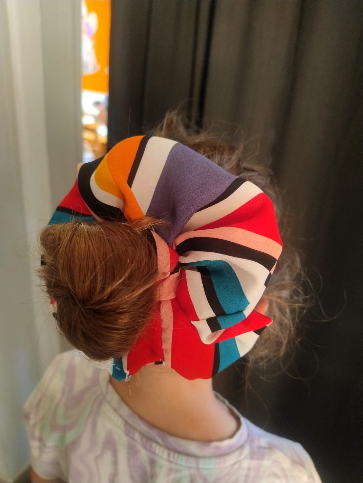 Dziewczyna z kokiem pozująca do zdjęcia, scrunchie w paski