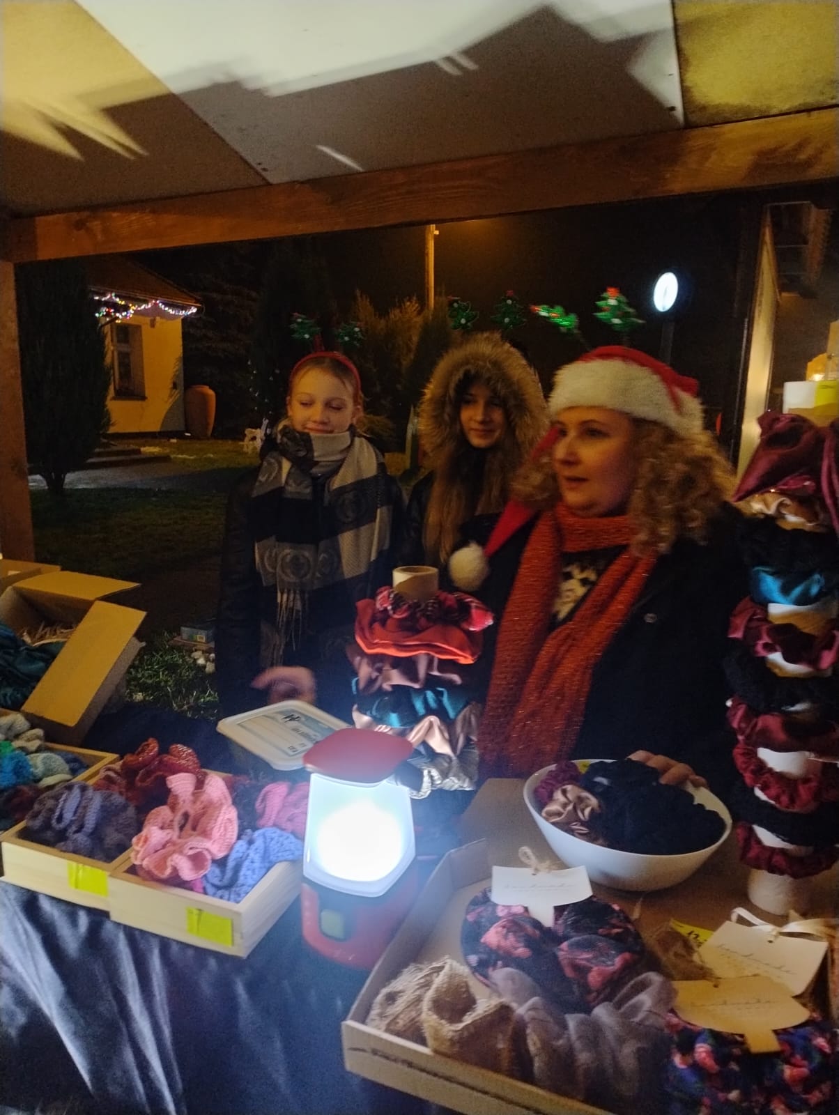 Trzy osoby przy stoisku świątecznym.