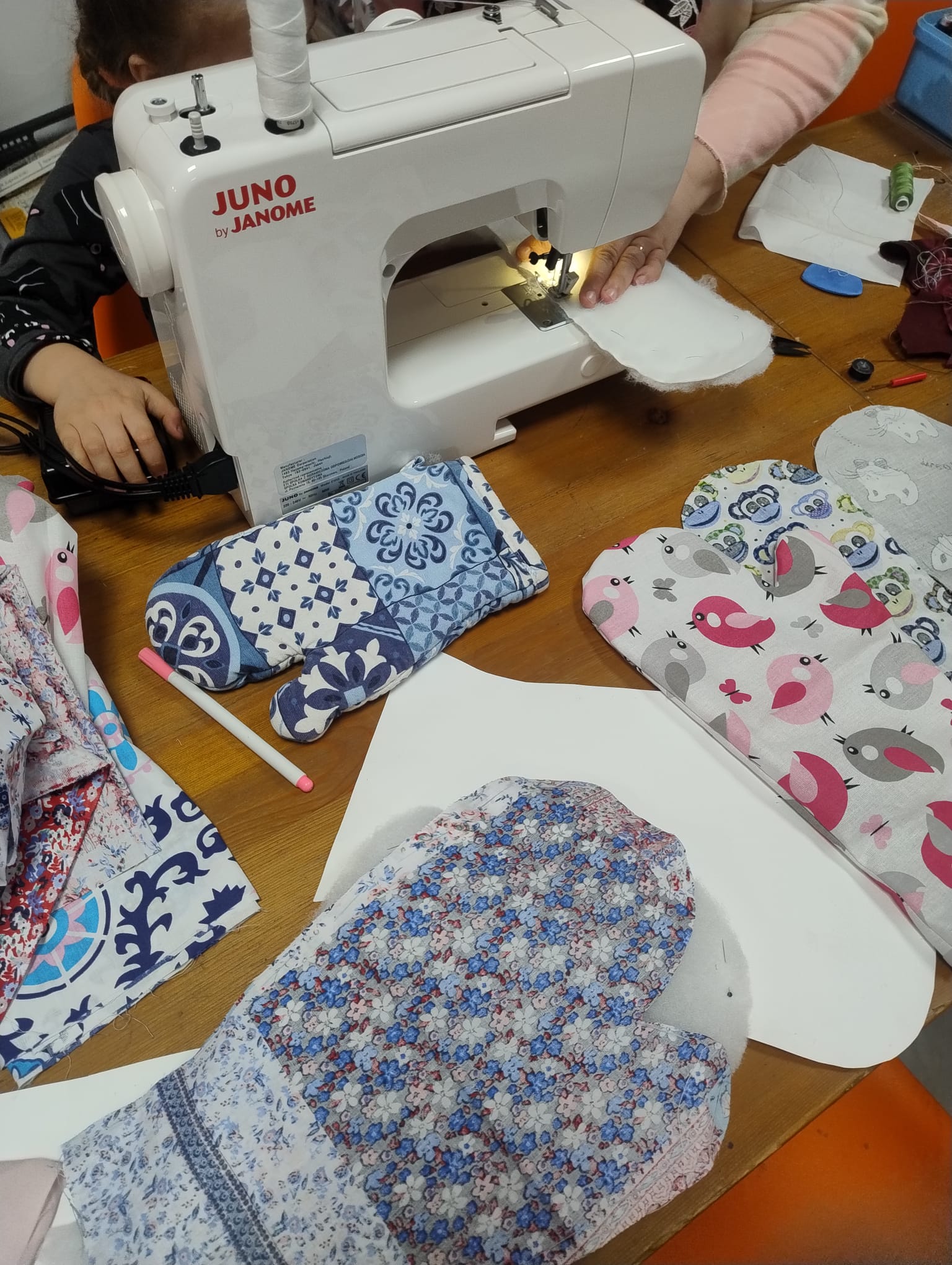 na zdjęciu maszyna do szycia i wykroje z materiałów, z których uszyjemy rękawice kuchenne