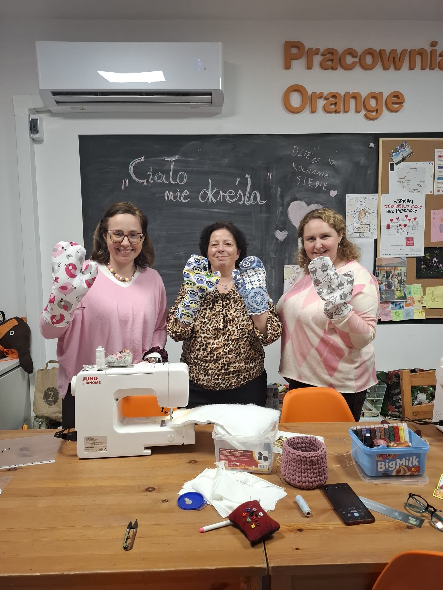 na zdjęciu trzy osoby, dorosłe kobiety trzymające w ręku rękawice kuchenne