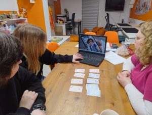 na zdjęciu trzy osoby oglądajace filmik Ciało nie określa, na stole leżą pomocnicze karty edukacyjne