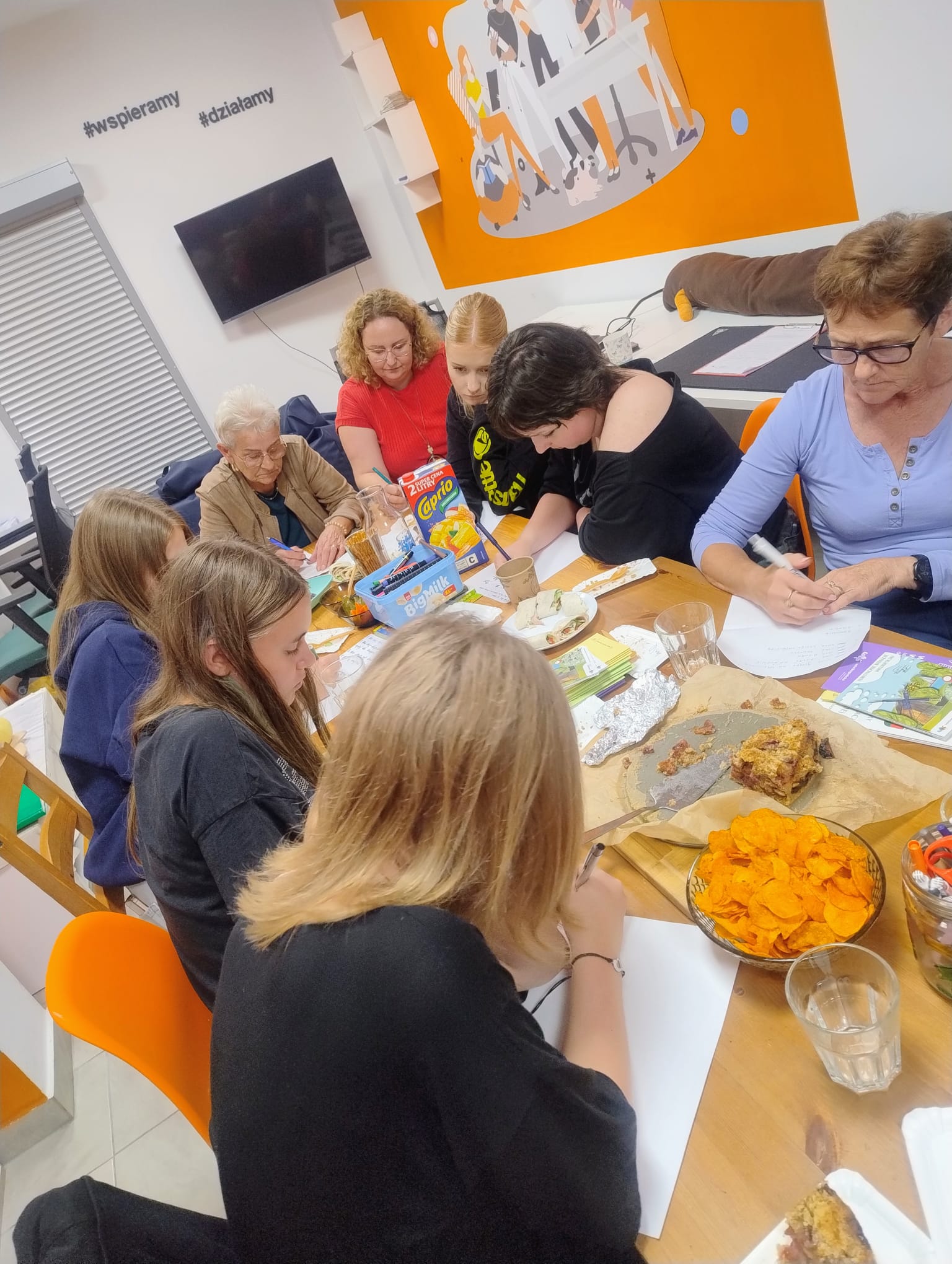 Grupa osób siedzących w Pracowni Orange podczas udziału w warsztatach.