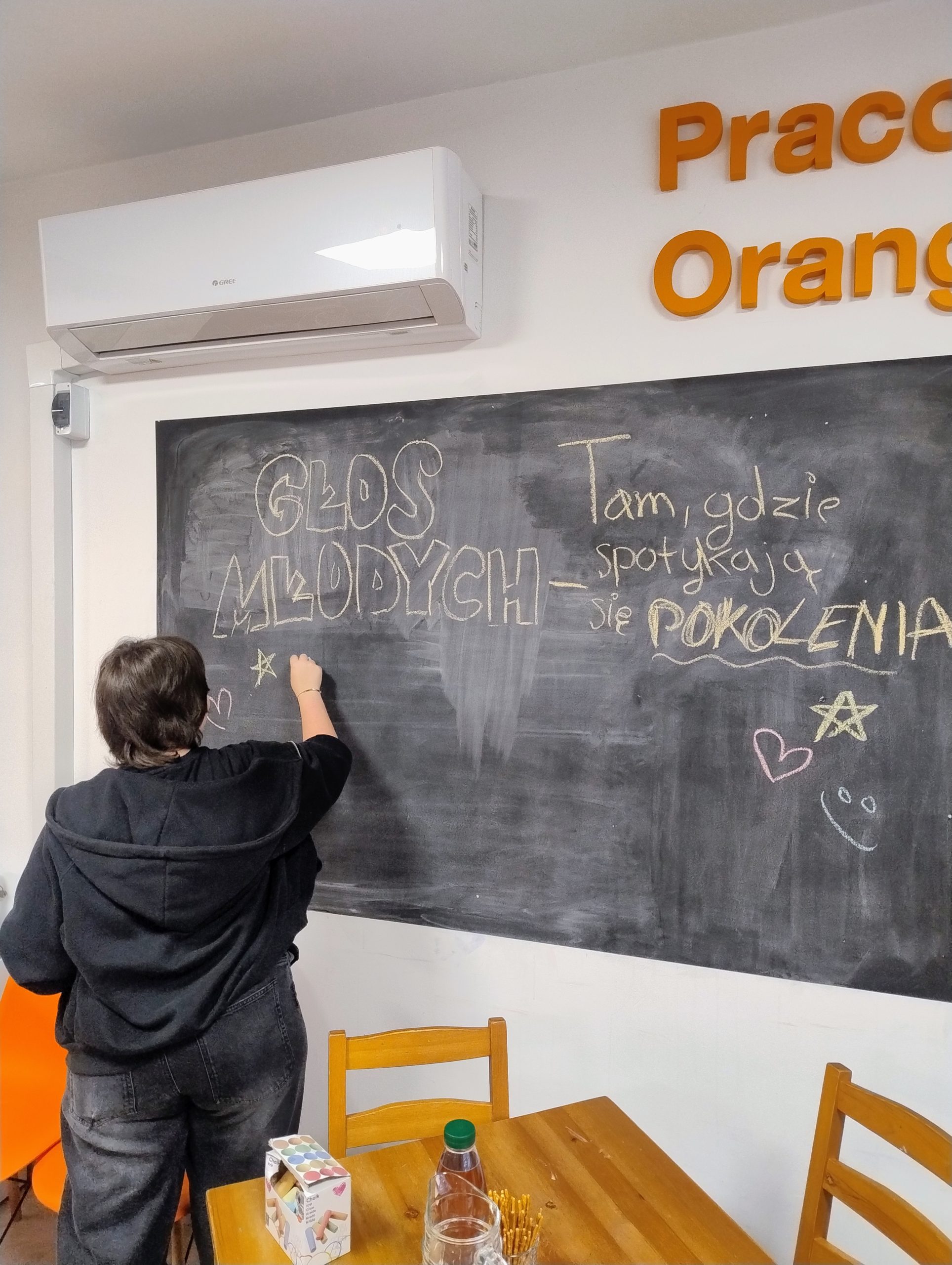 liderka młodzieżowa pisze kredą tytuł projektu na tablicy ściennej