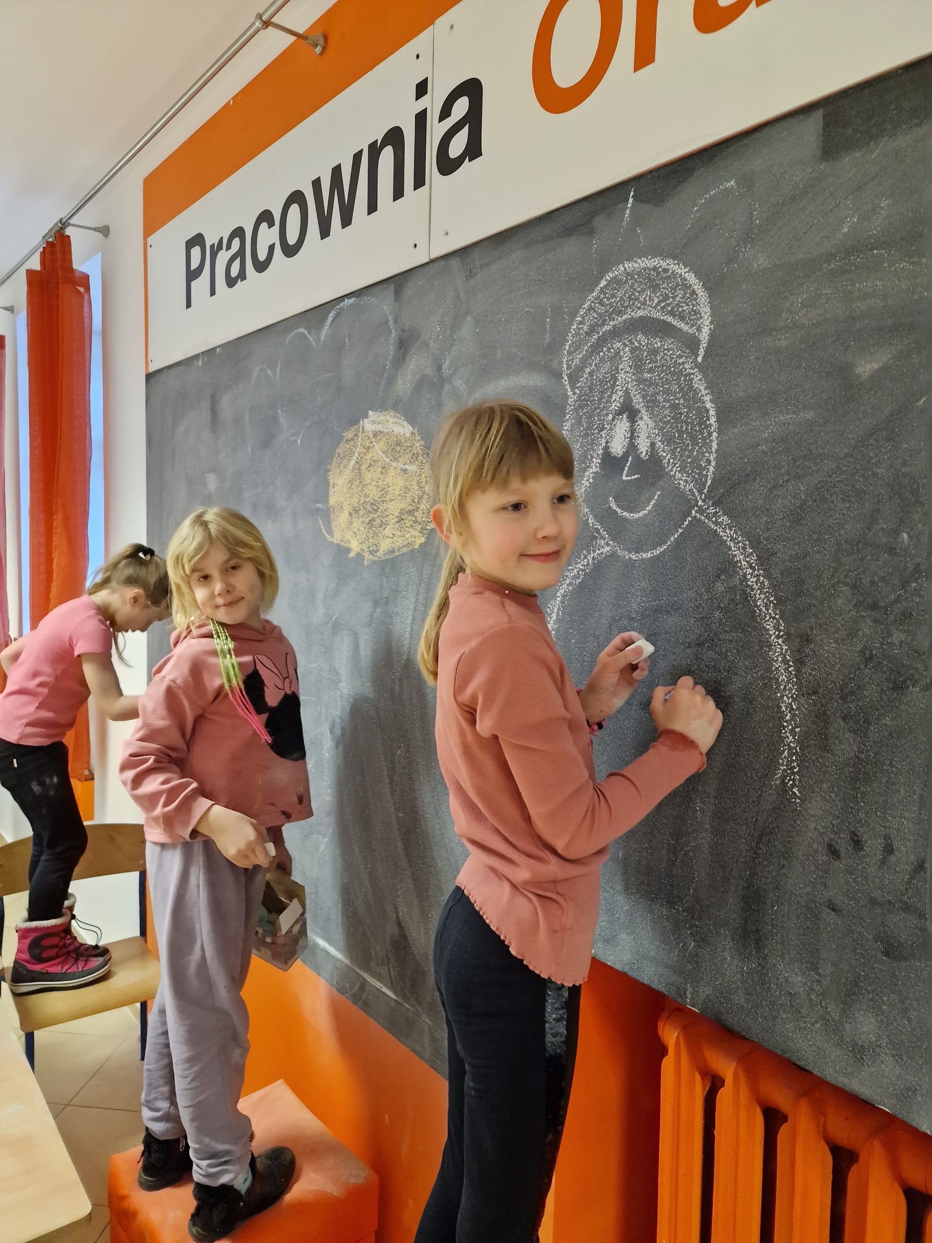 dzieci rysujace na tablicy kredą podobizny babć