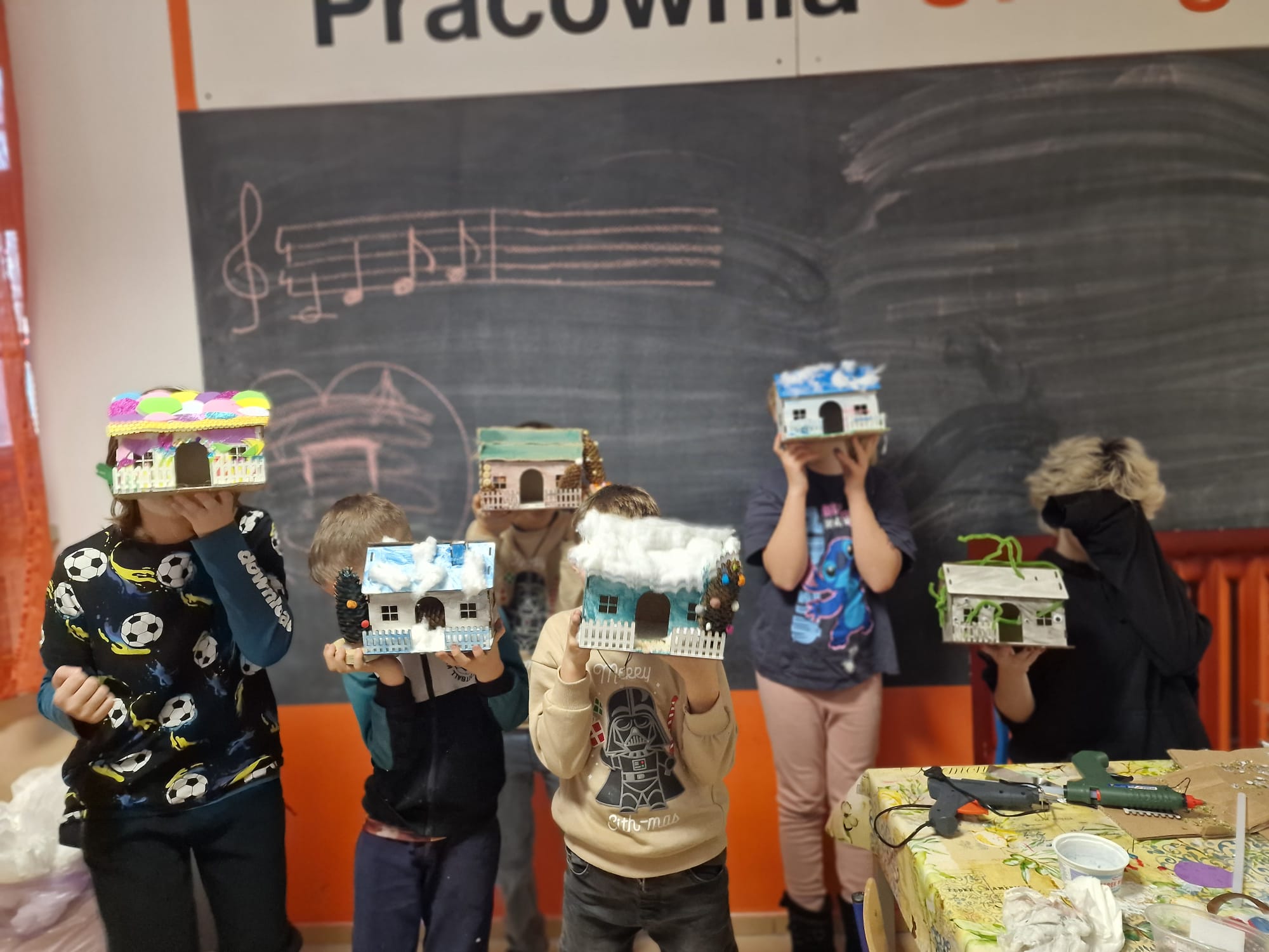 Grupa dzieci pozuje do zdjęcia z wykonanymi domkami.