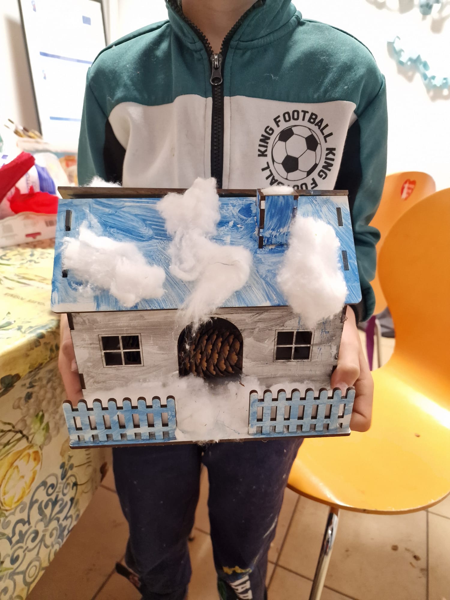 Dziecko pozuje do zdjęcia z wykonanym domkiem.