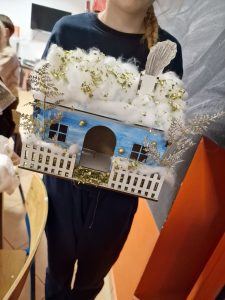 Dziecko pozuje do zdjęcia z wykonanym domkiem.