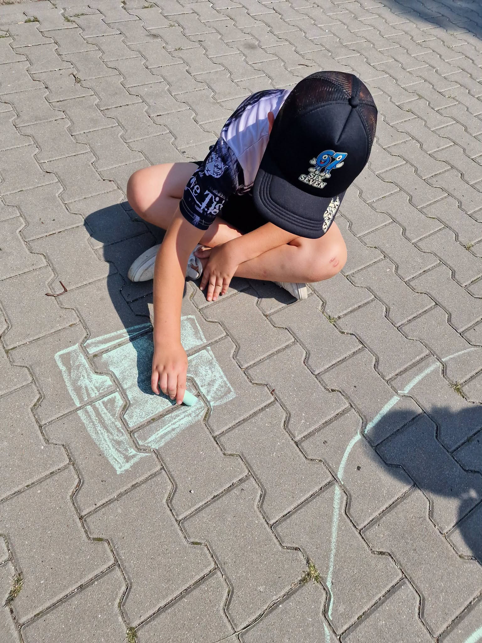 Dziecko maluje kredą na chodniku