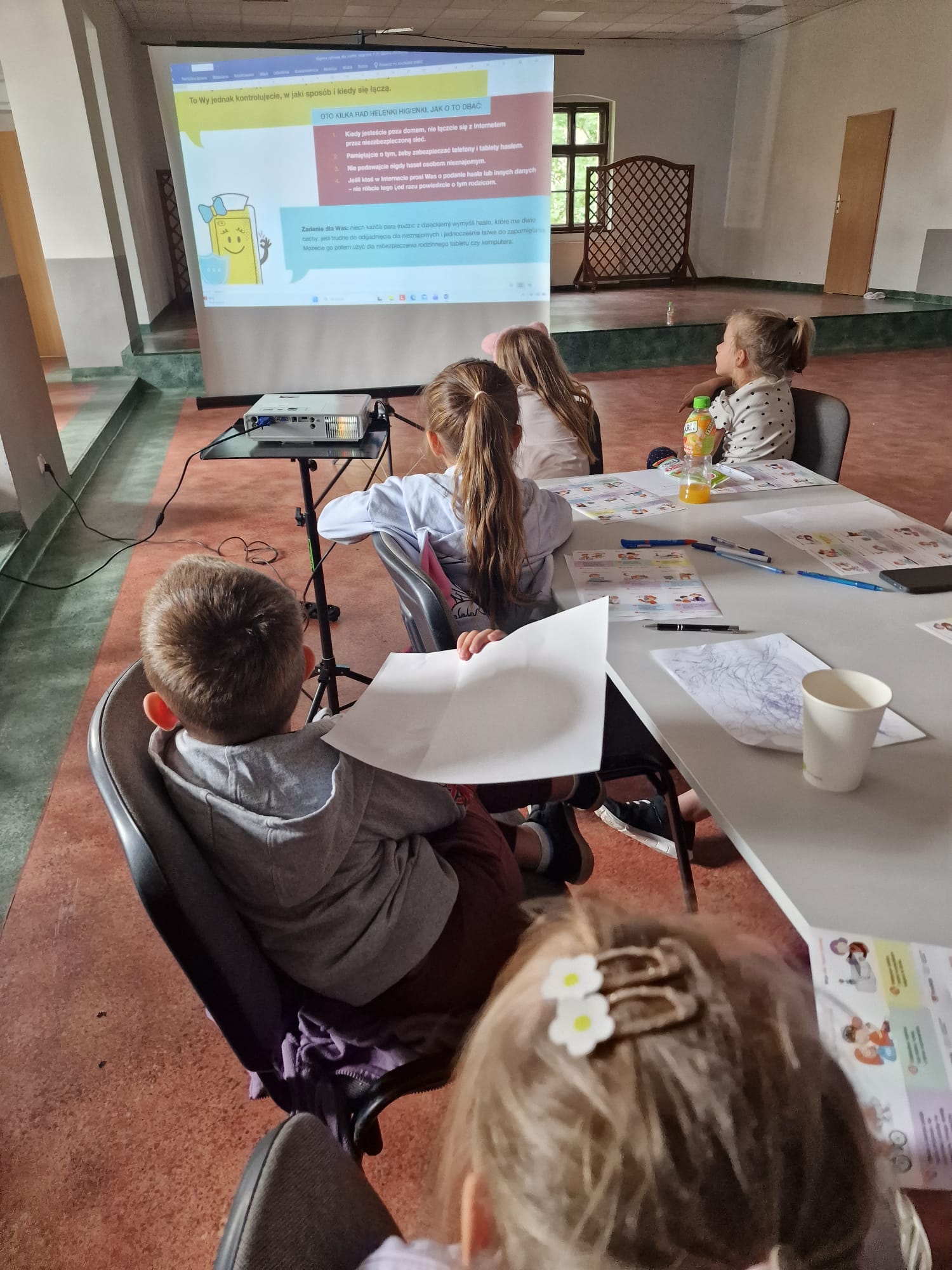 Dzieci oglądają prezentację wyświetloną na ekranie.