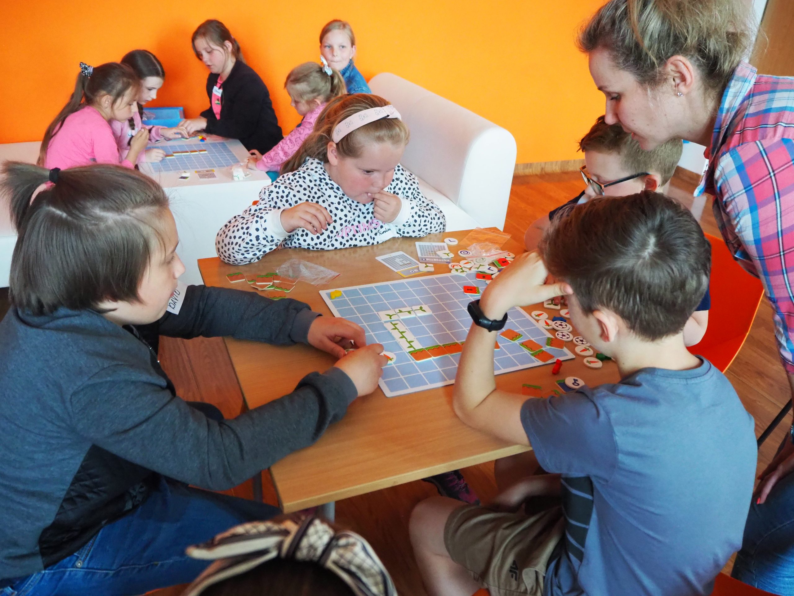 grupa dzieci siedzi przy stole podczas Zajęć z kodowania
