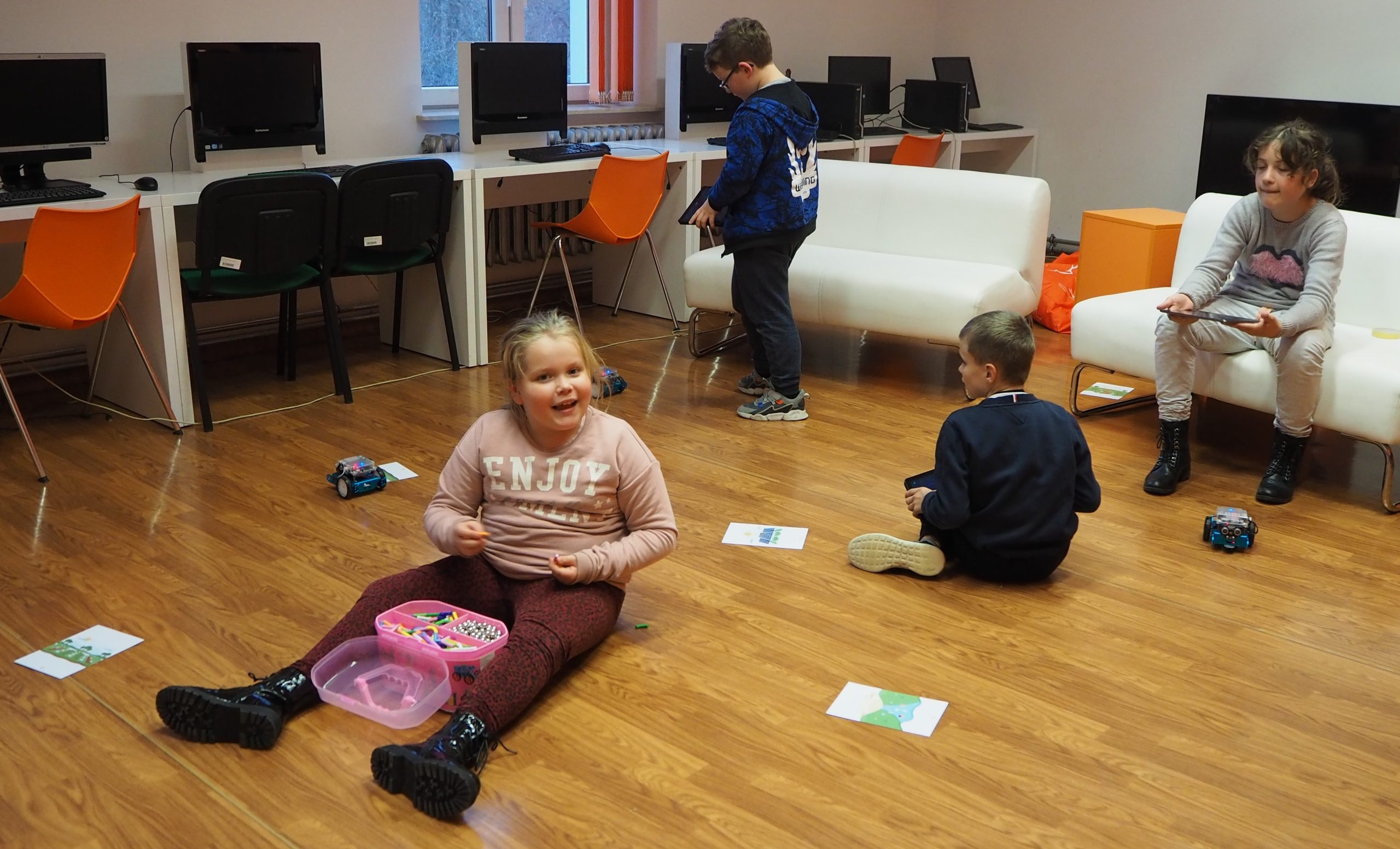 uśmiechnięte dzieci siedzą na podłodze podczas zajęć warsztatowych