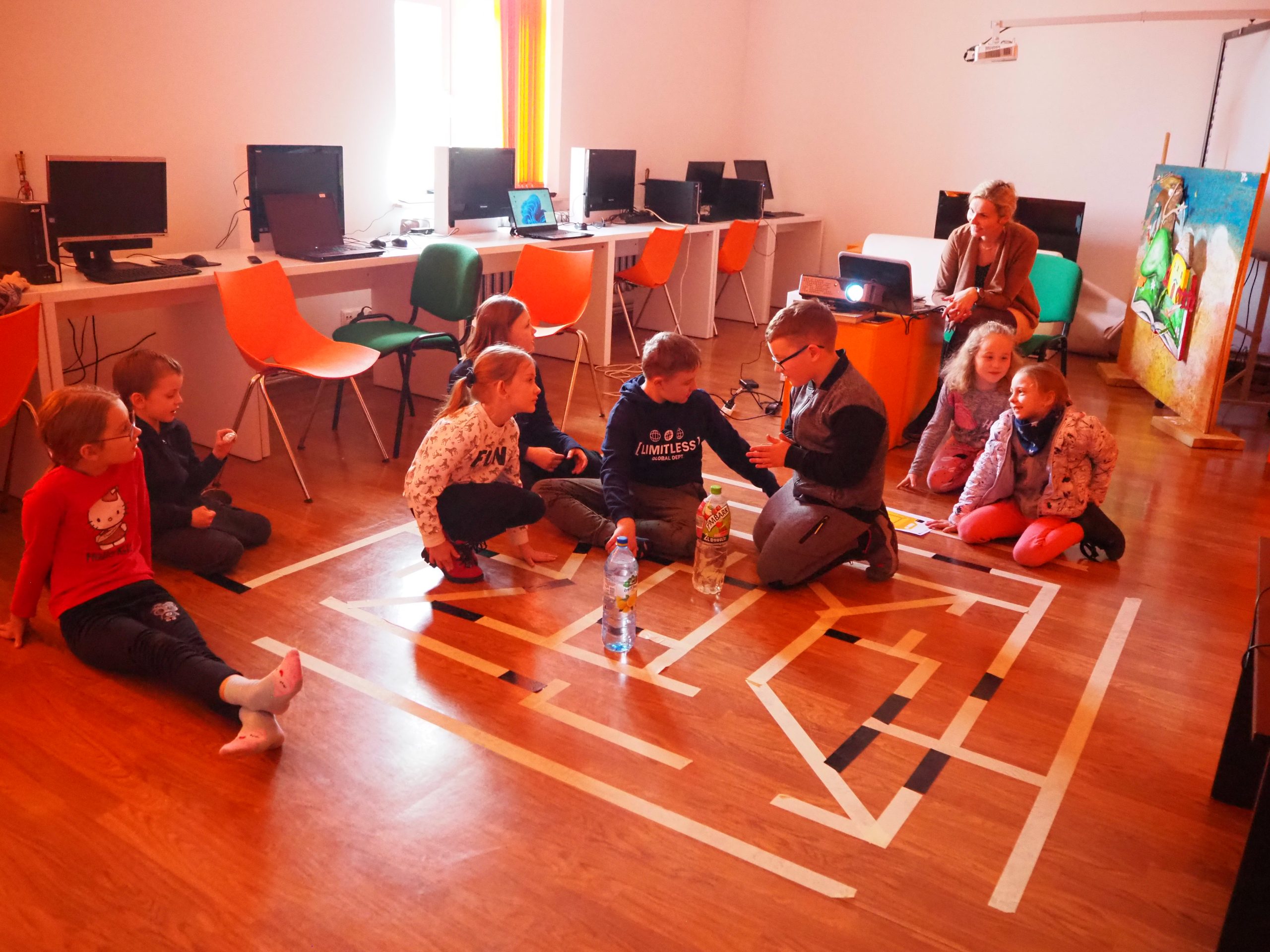 Dzieci siedzące na podłodze podczas zabaw warsztatowych.