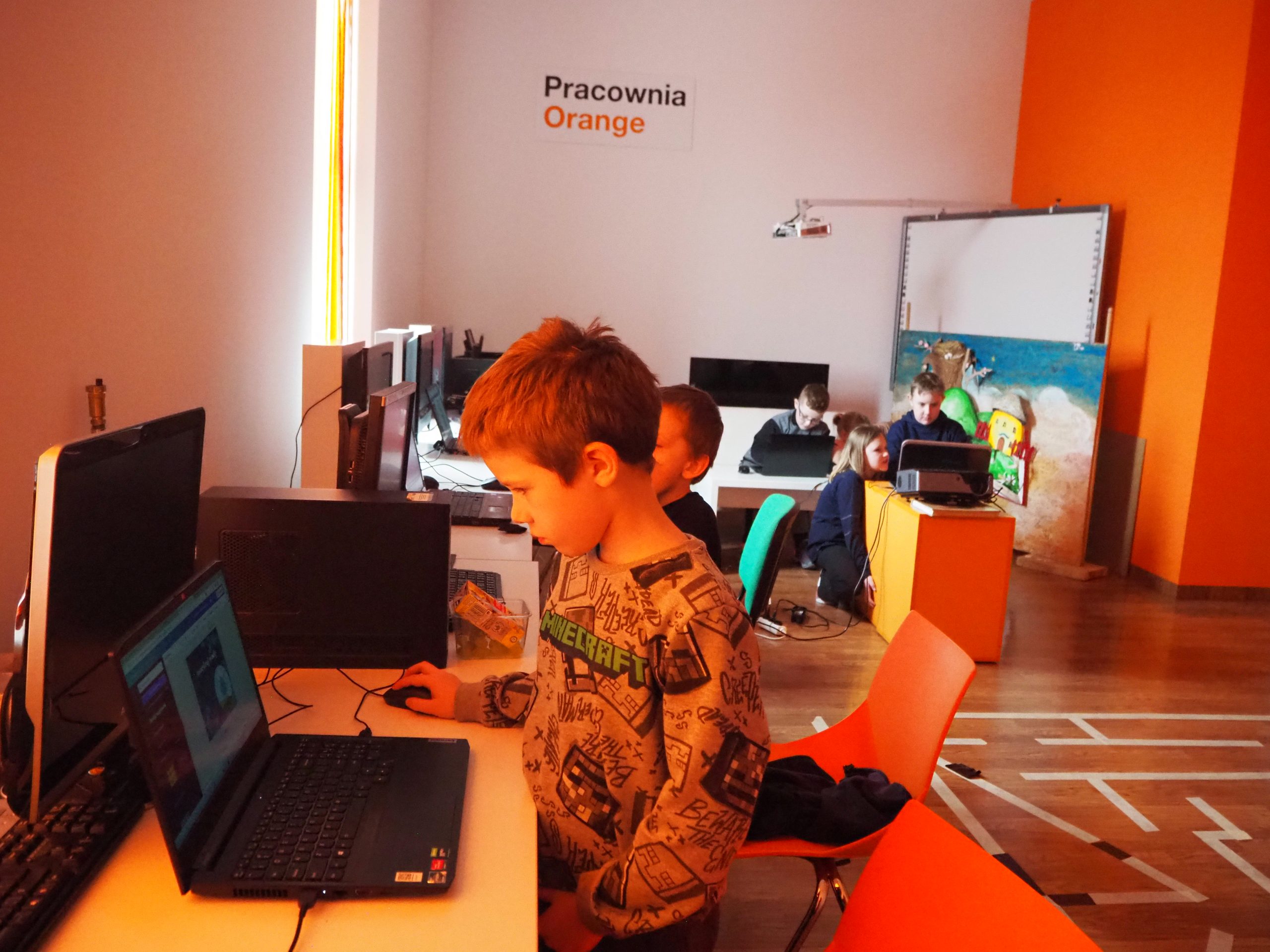 dzieci przy laptopie w pracowni orange robią projekt w programie graficznym