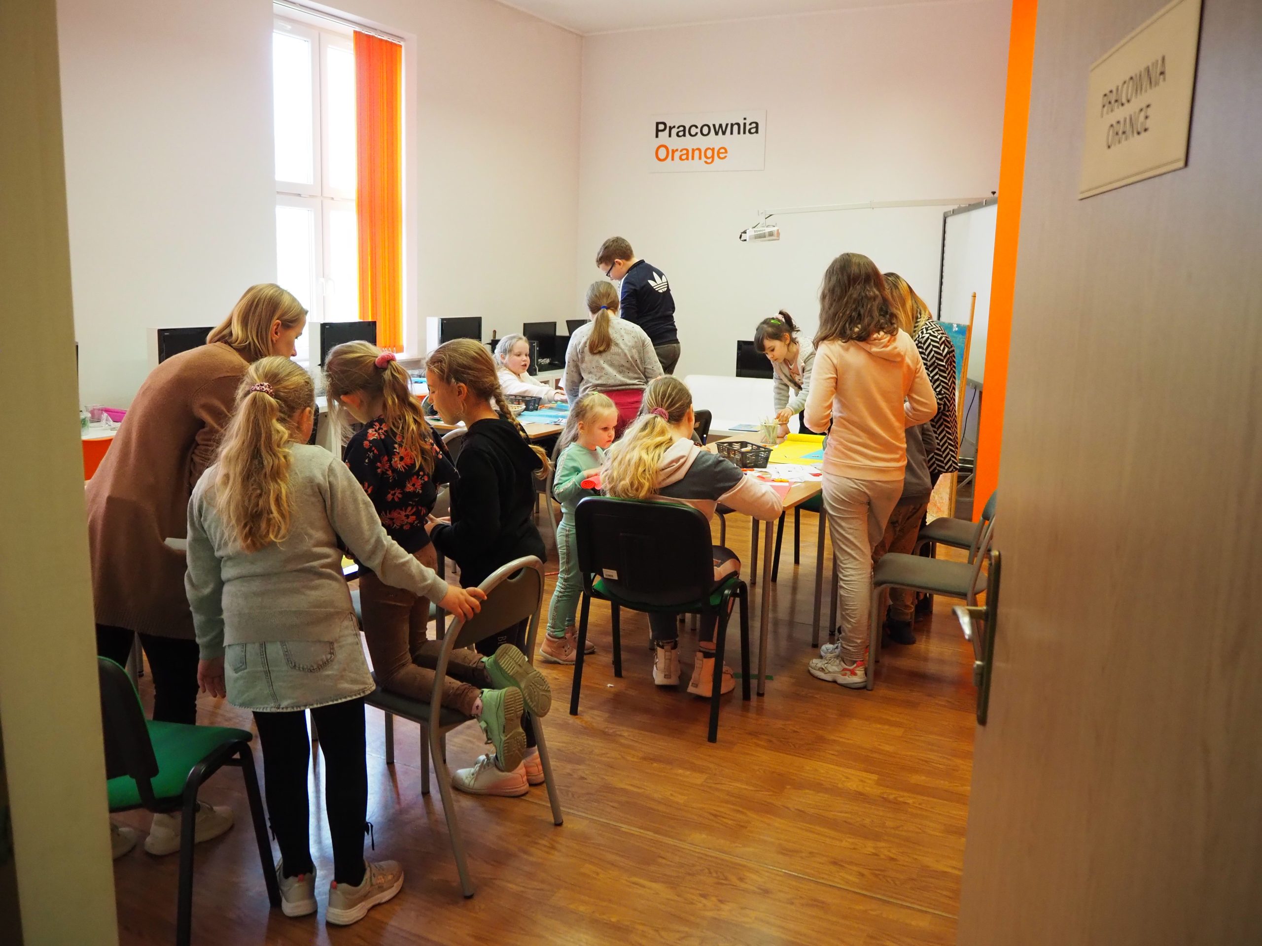 grupa dzieci przy stołach w pracowni orange integrują się razem