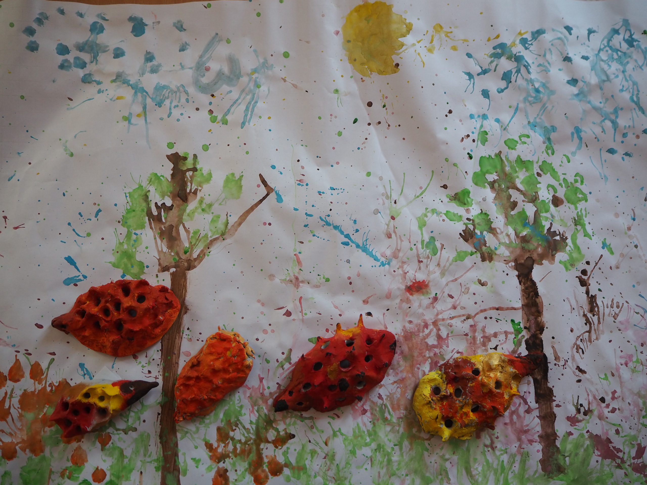 zdjęcie przedstawia obrazek na którym zostały namalowane drzewa i doklejone jeże z plasteliny
