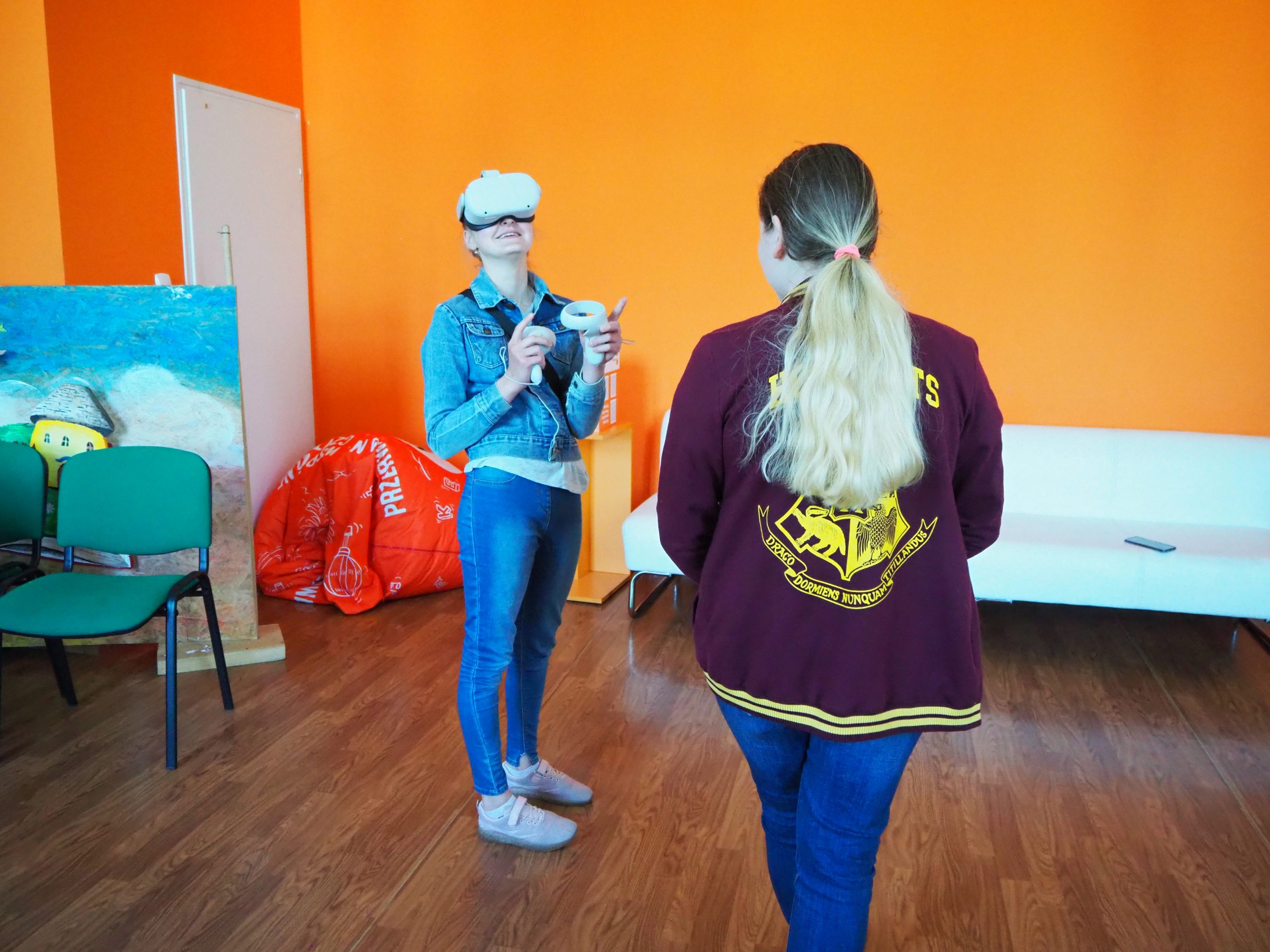 dwie kobiety stoją w pracowni orange, jedna z ich odwrócona jest plecami a druga korzysta z gogli do wirtualnej rzeczywistości