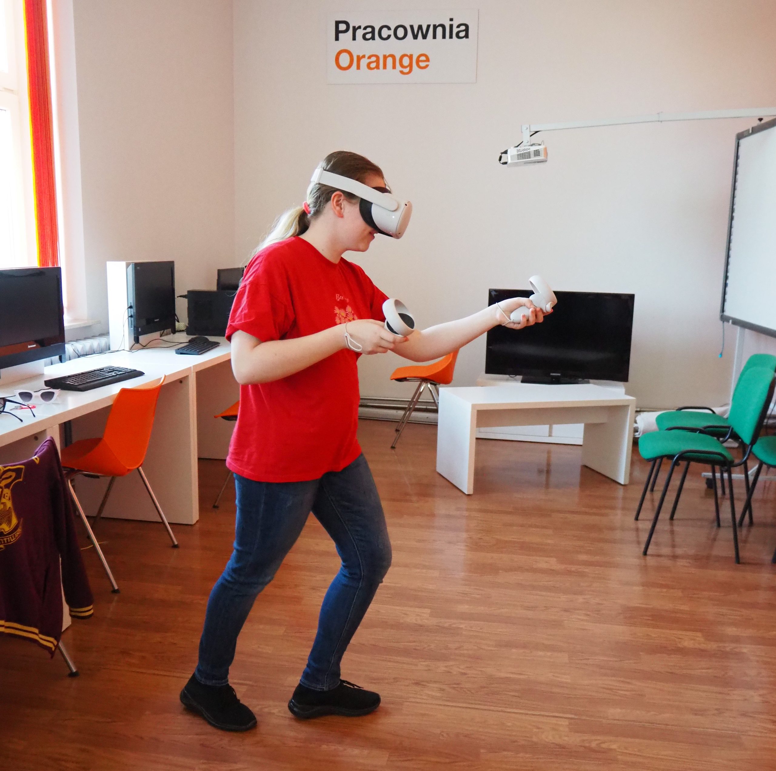 kobieta w czerwonej bluzce w pracowni orange korzysta z gogli do wirtualnej rzeczywistości