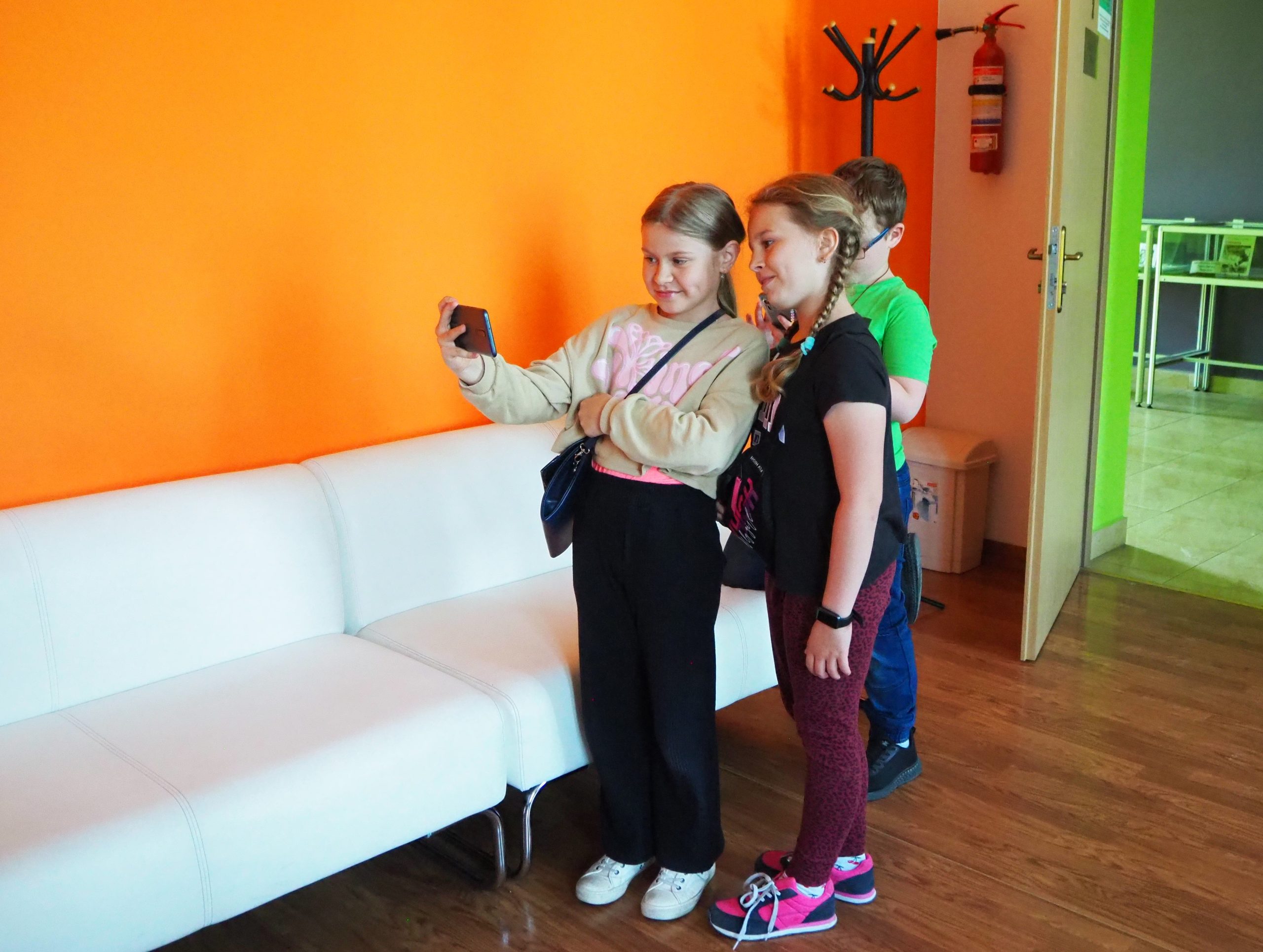 dwie dziewczynki i chłopiec robią sobie selfie w pracowni orange