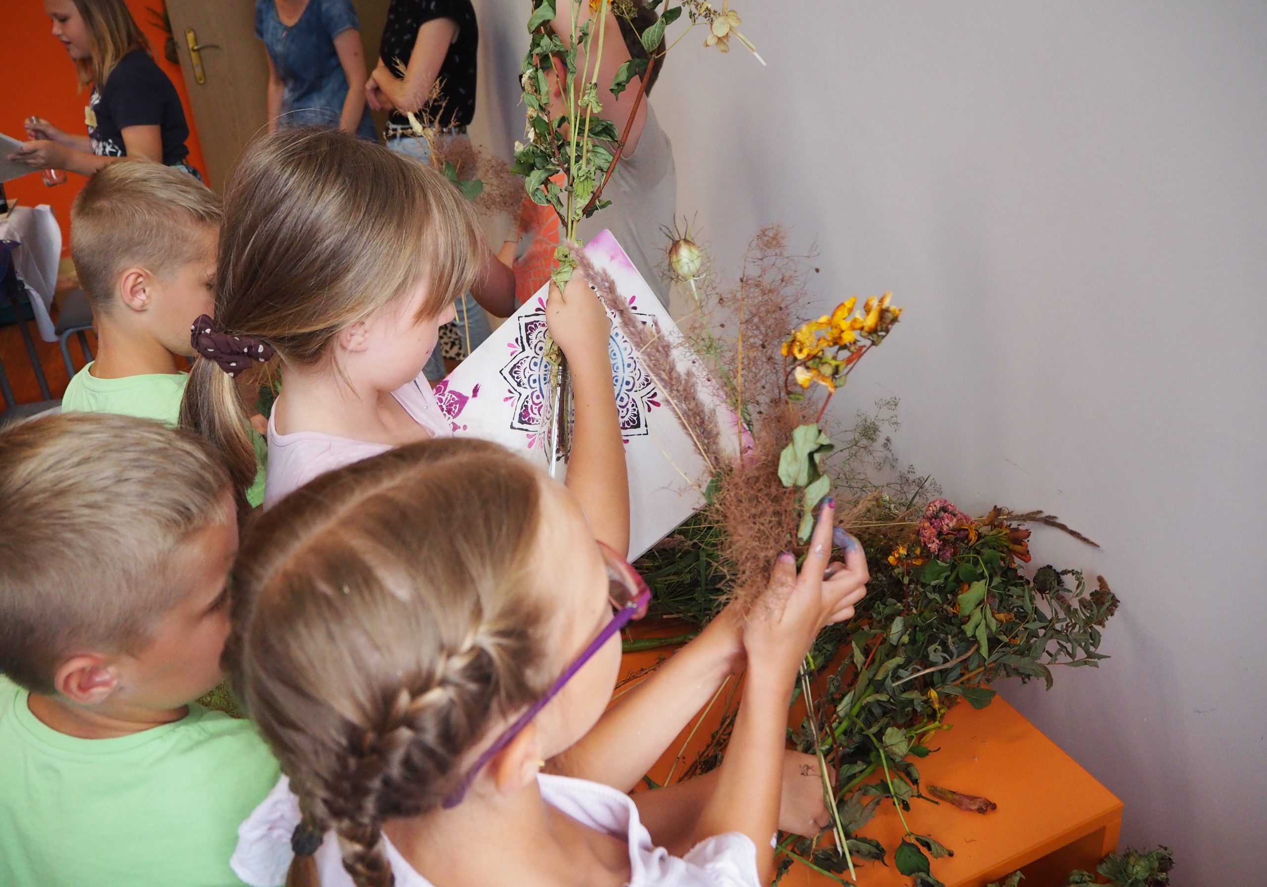 grupa dzieci wybiera suszone kwiaty do wykonania swoich prac