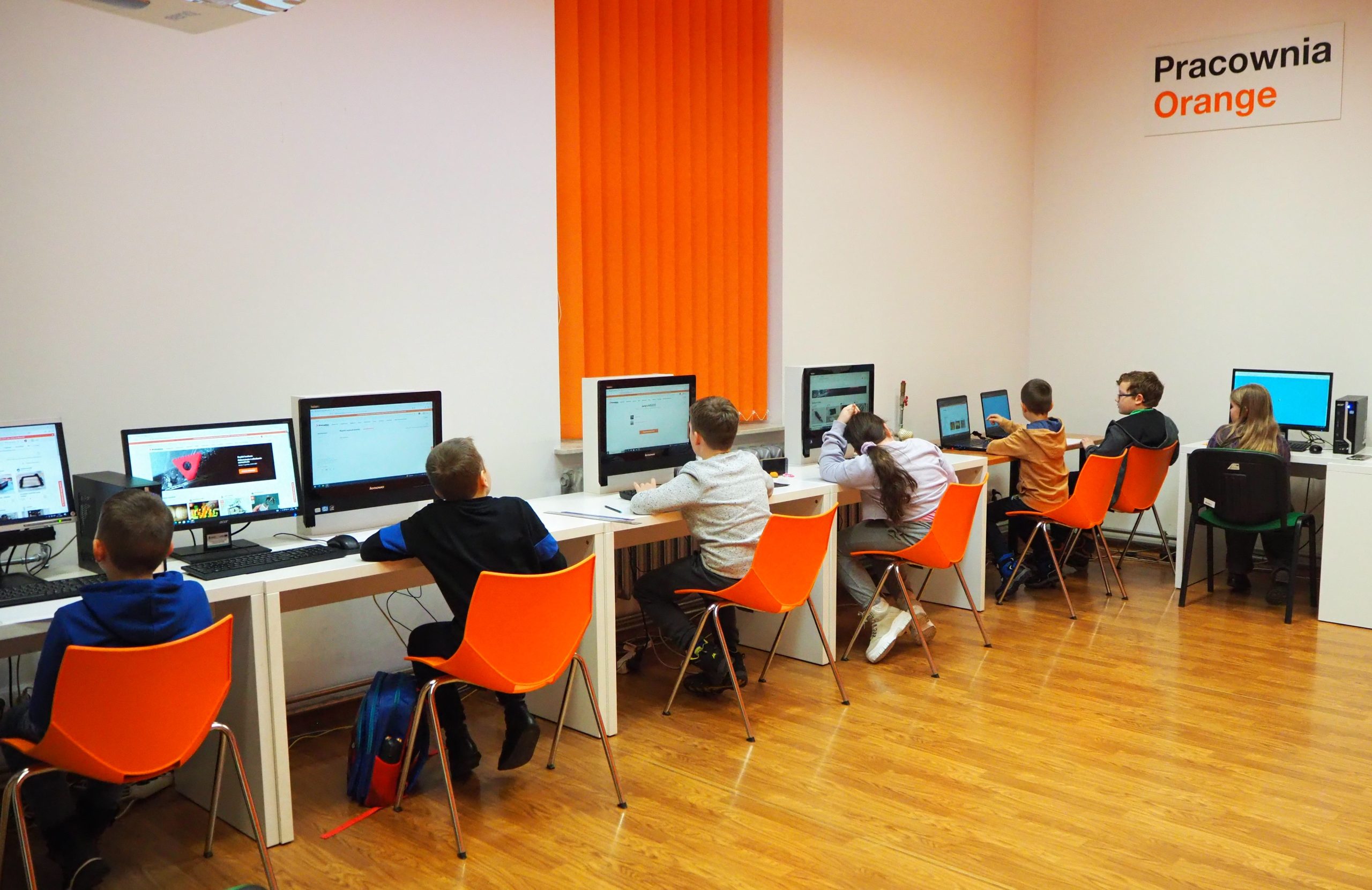 grupa dzieci przy komputerach w pracowni orange