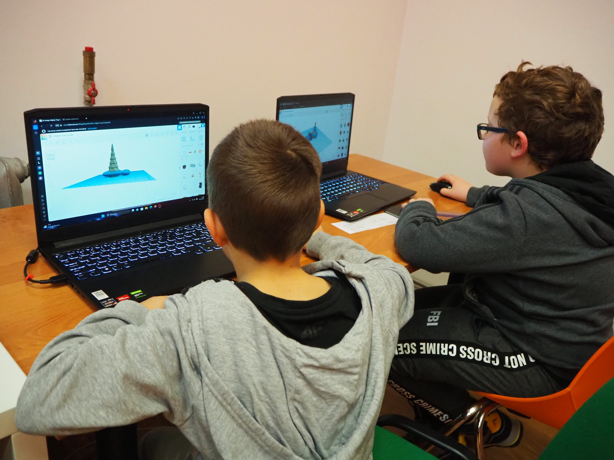 Dwaj chłopcy siedzący przy komputerach.