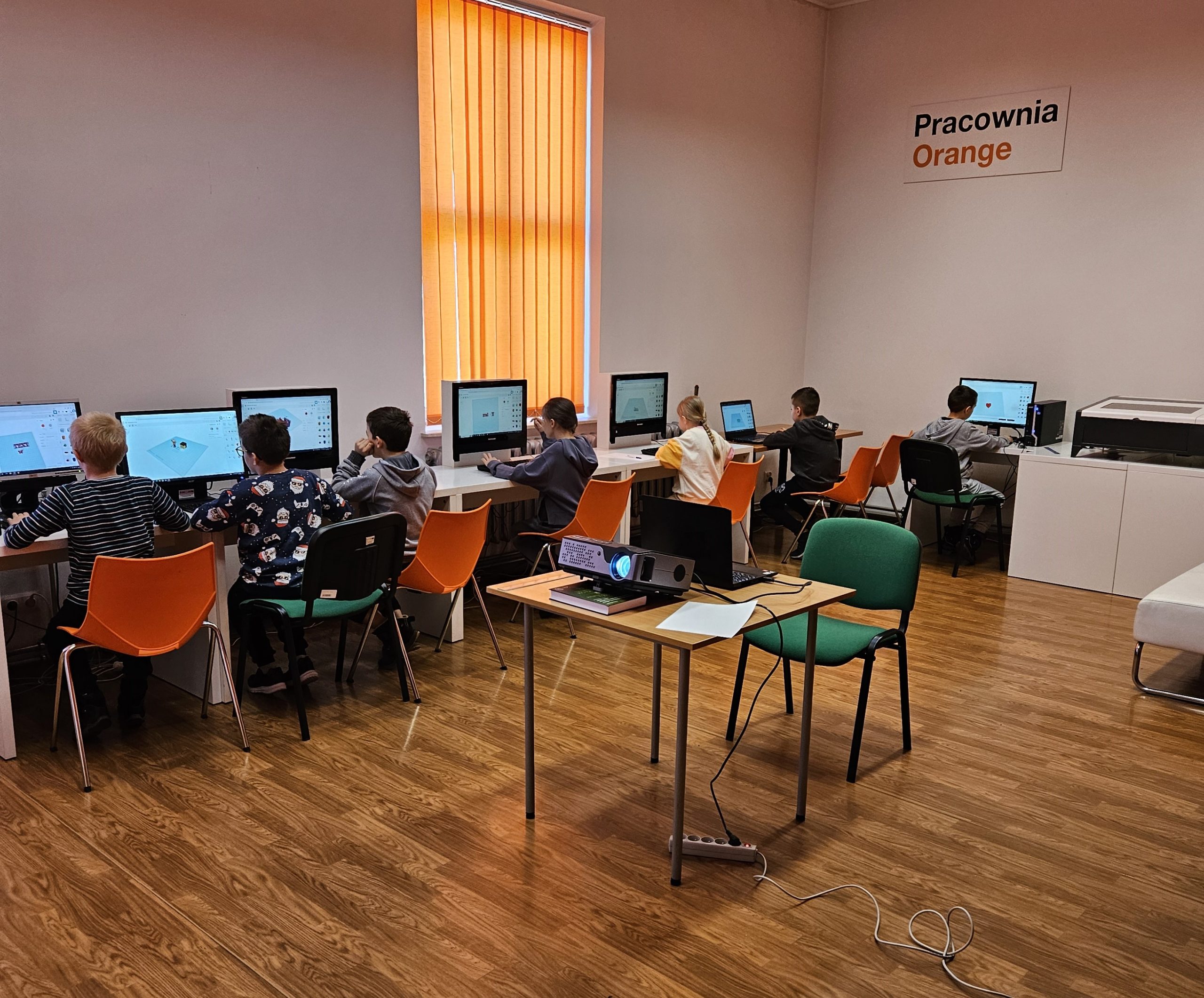 Grupa dzieci siedzących przy komputerach.