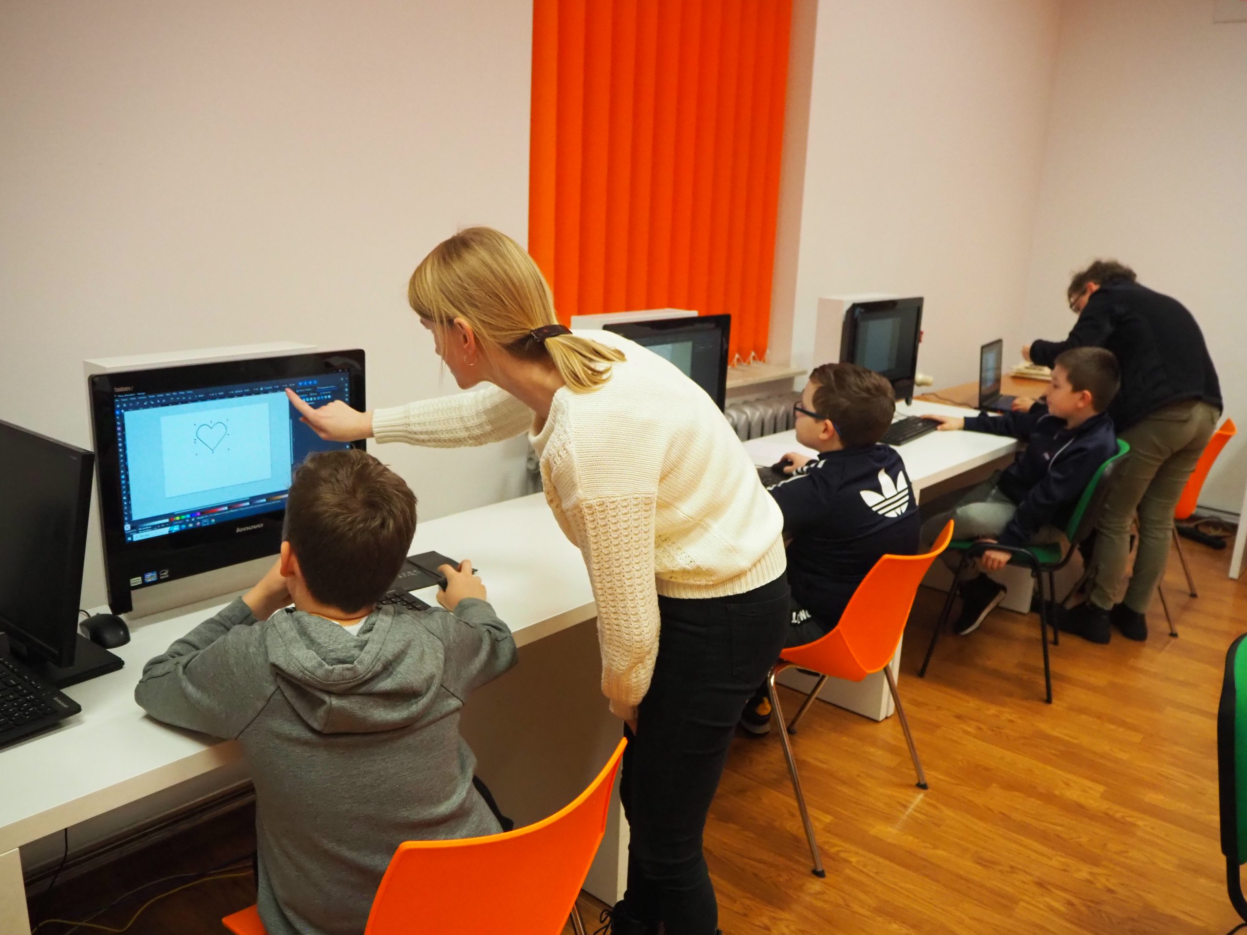 Chłopcy projektują na komputerach serduszka.
