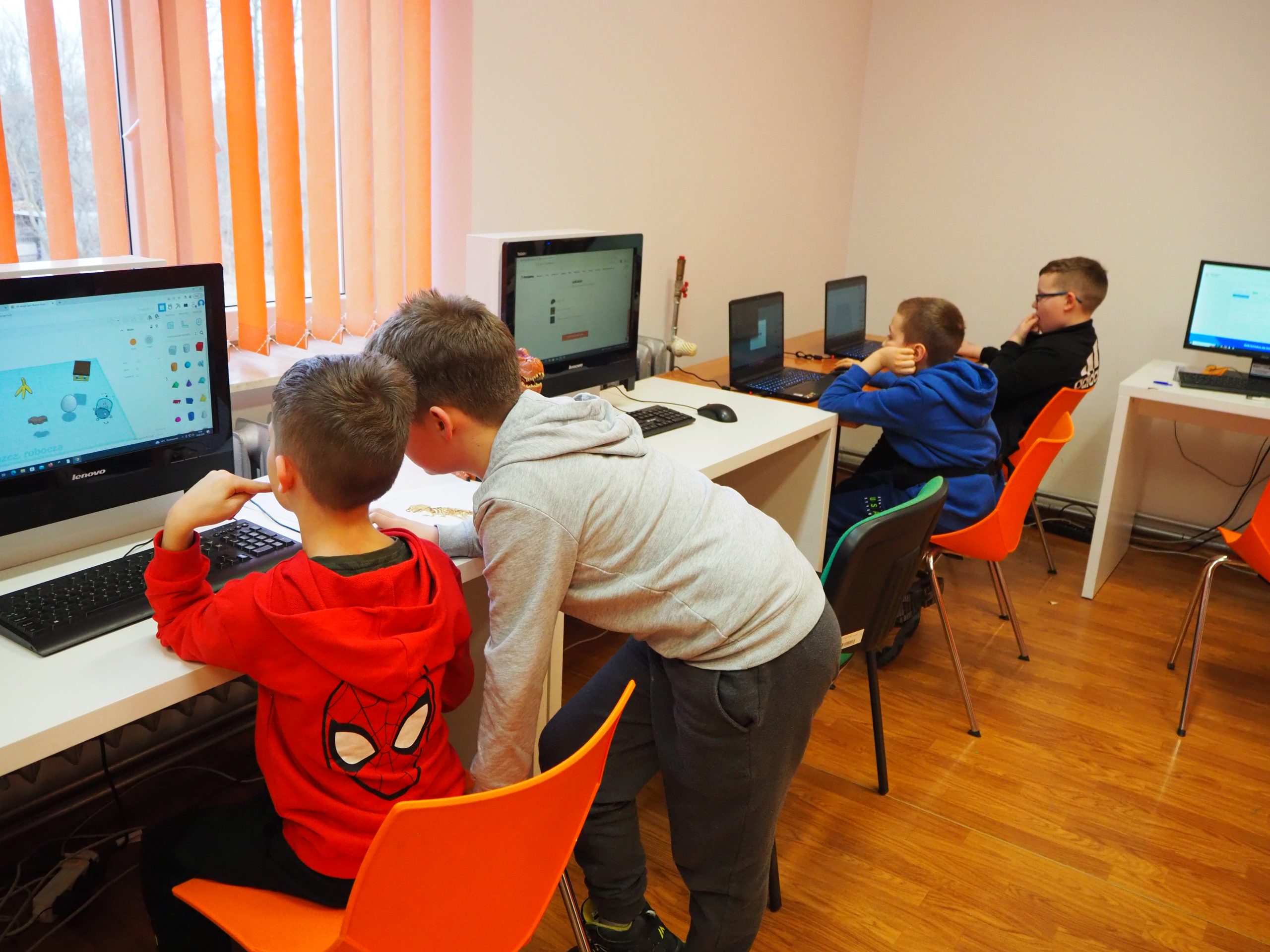 Grupa dzieci projektuje szkielet dinozaura na komputerze.