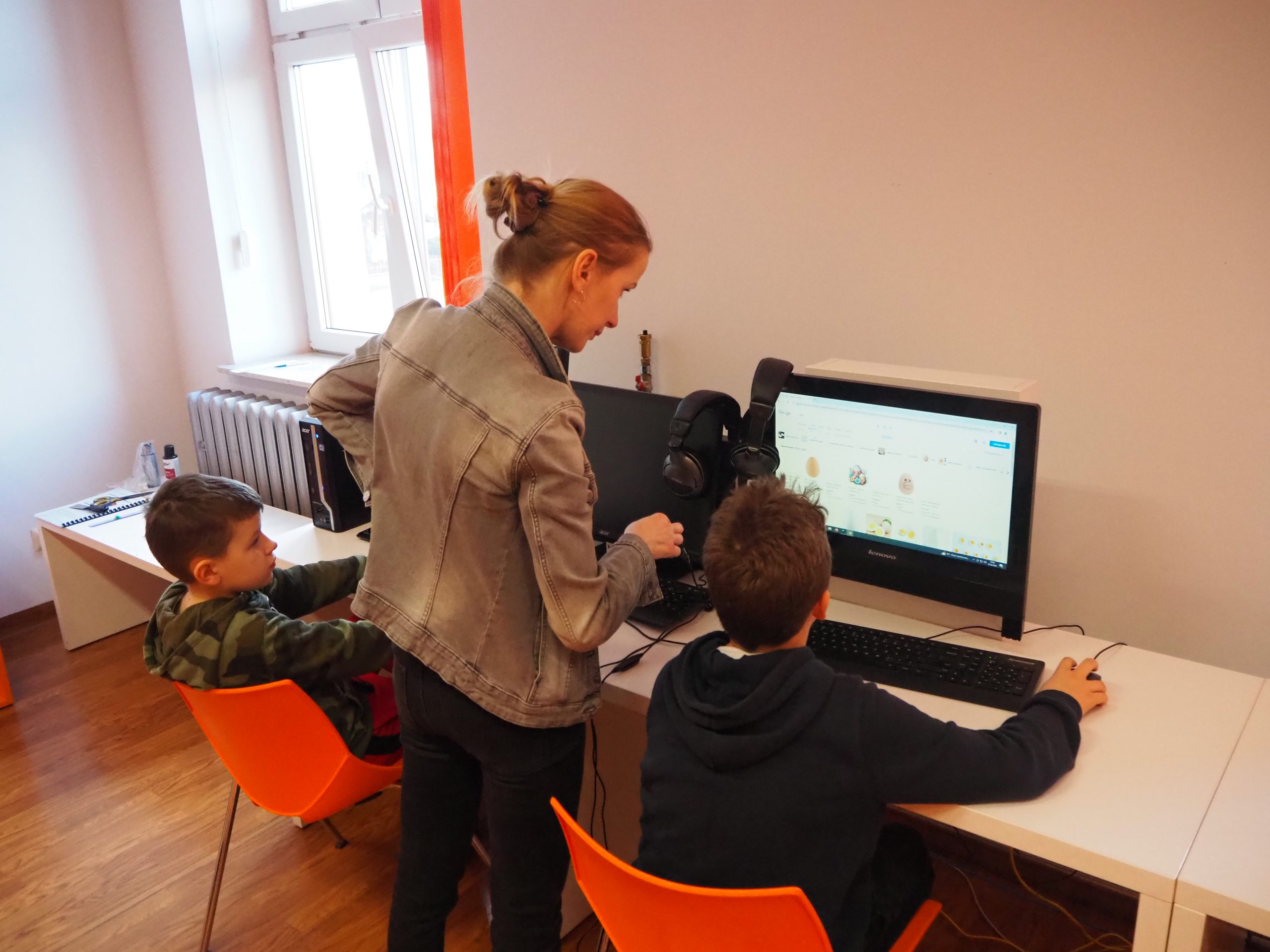 Uczestnicy warsztatów i prowadząca projektują przy komputerach.