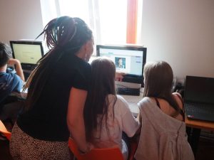 Pani prowadząca zajęcia z dwiema dziewczynkami przed monitorem