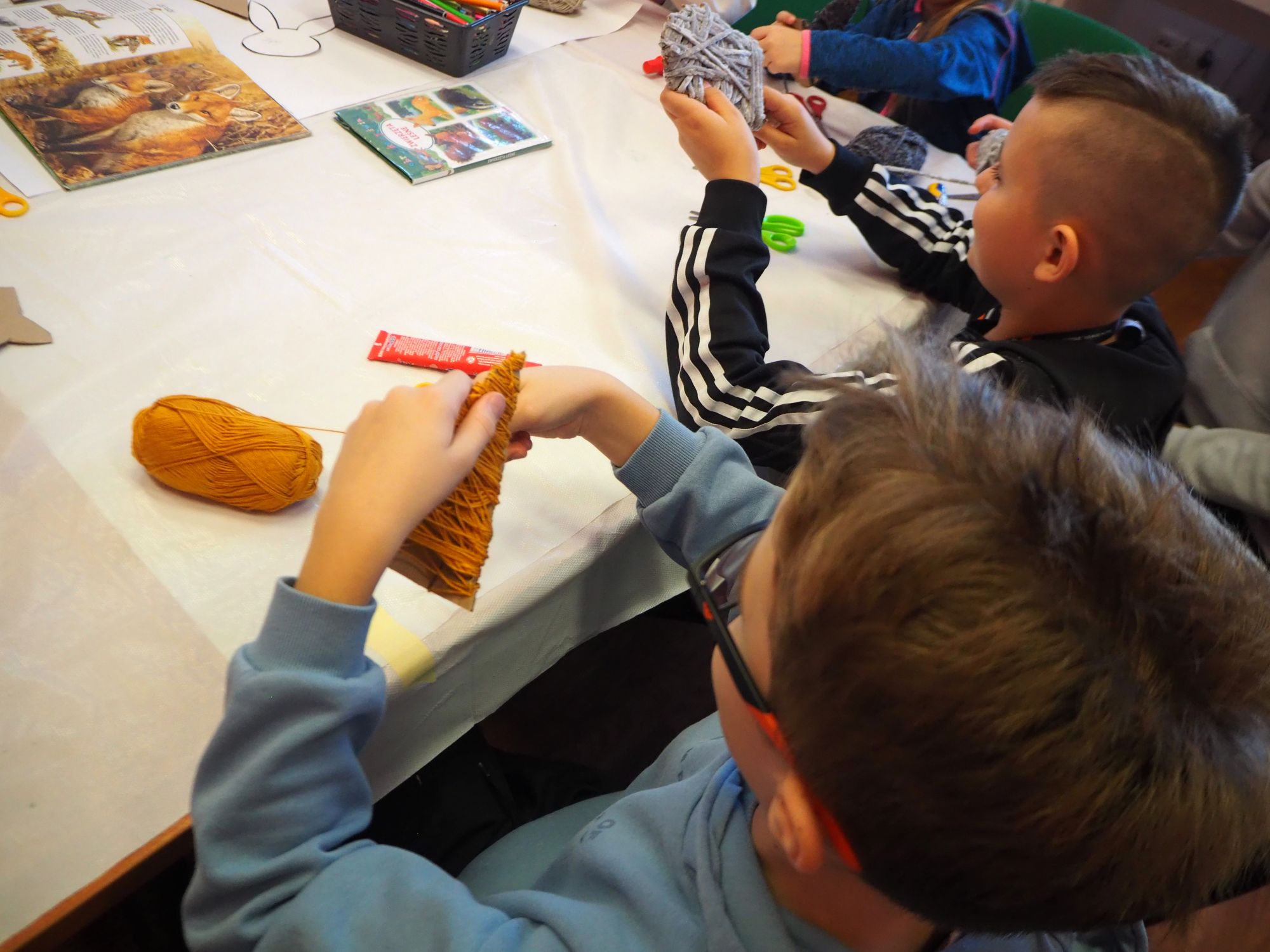 chłopiec wykonuje liska z włóczki i tektury