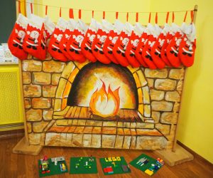 na zdjęciu widać kominek sztuczny a pod nim na zielonych deseczkach zrobione różne elementy z bajki Olaf