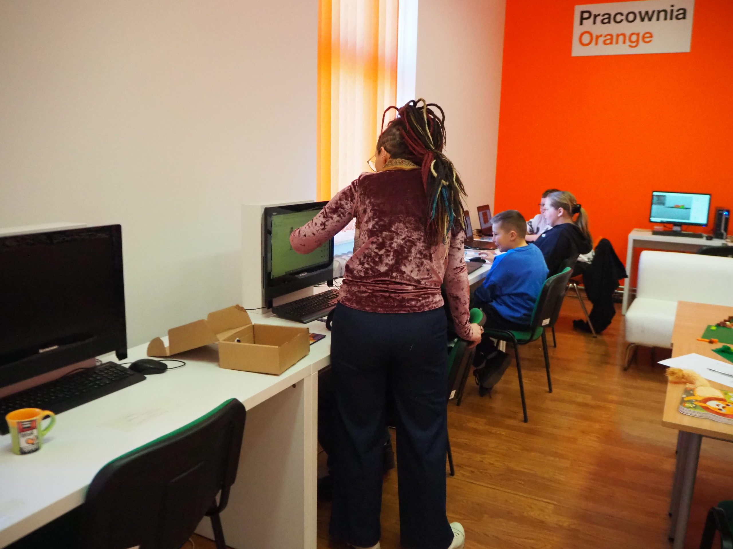 dzieci siedzą prze komputerami i projektują postacie z gry Minecraft