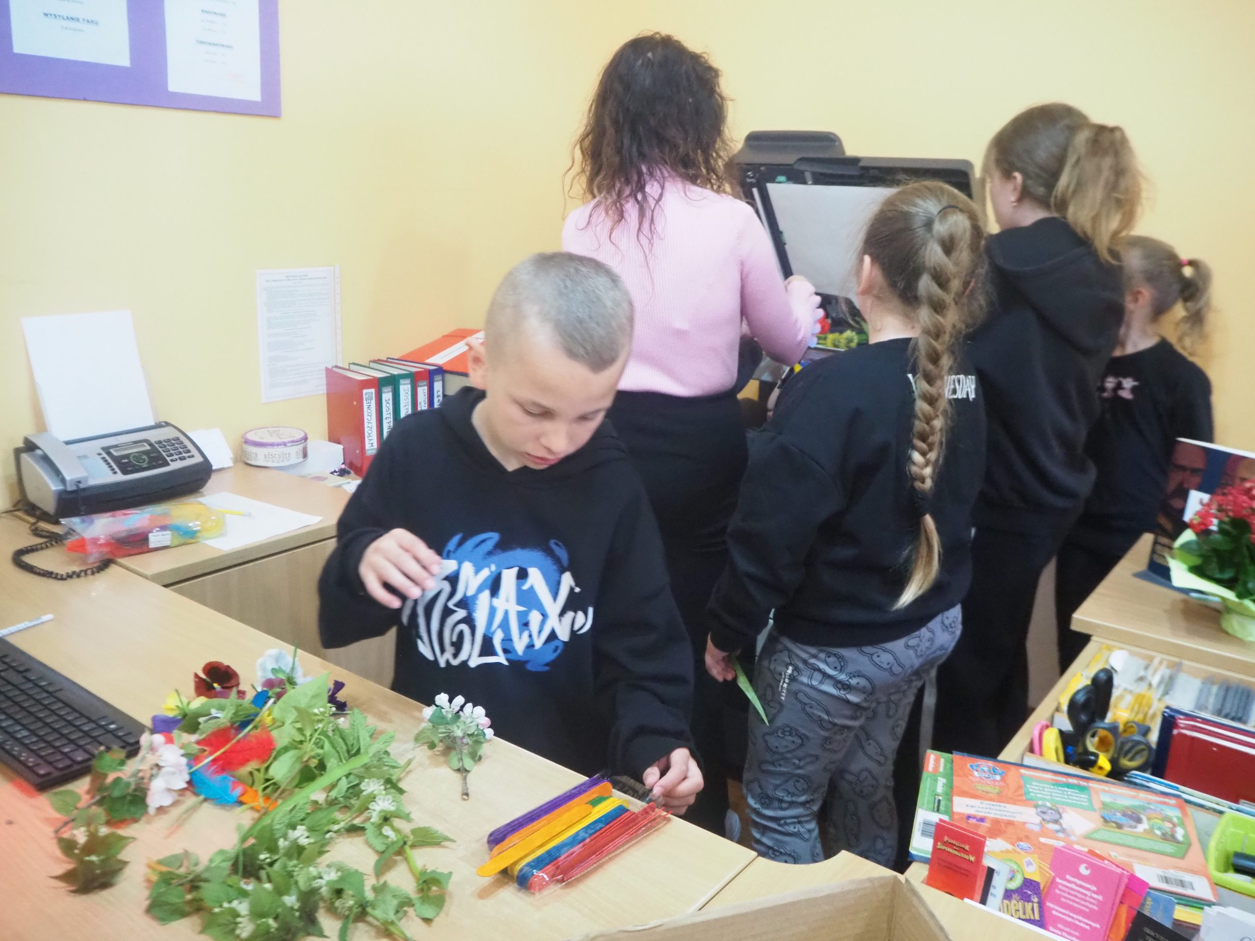 dzieci z Panią stoją przy skanerze, a chłopiec wybiera co zeskanować