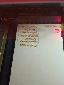 ploter laserowy wycina etykietkę z napisem Dzień Edukacji Narodowej Cieszanów