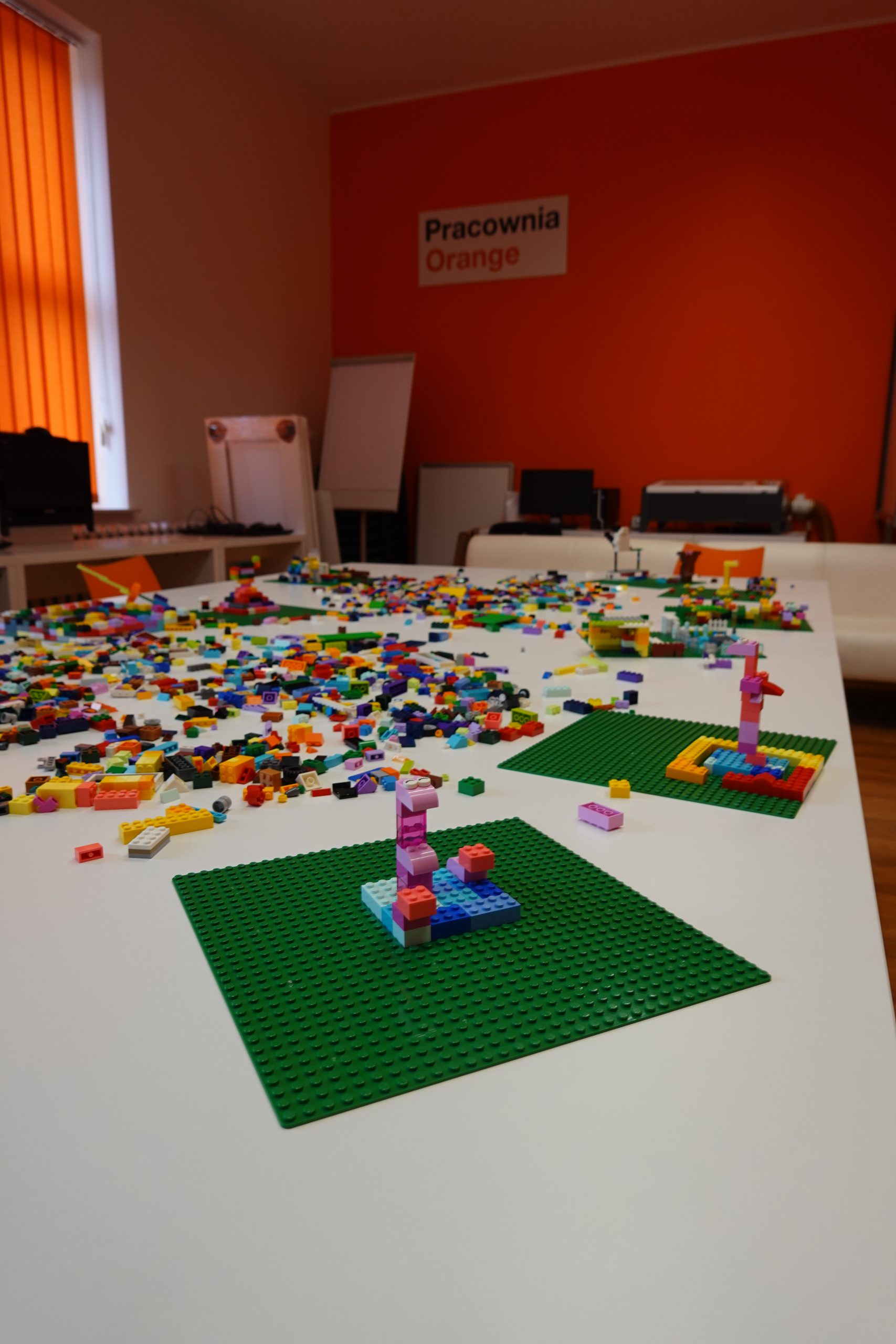 na stołach rozsypane klocki lego i budowle zrobione przez dzieci