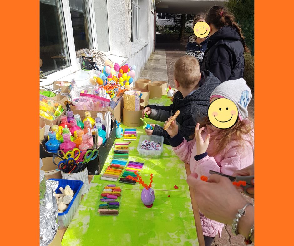 Dzieci przy stole wykonujące figurki ze styropianowych jajek, plasteliny i piórek