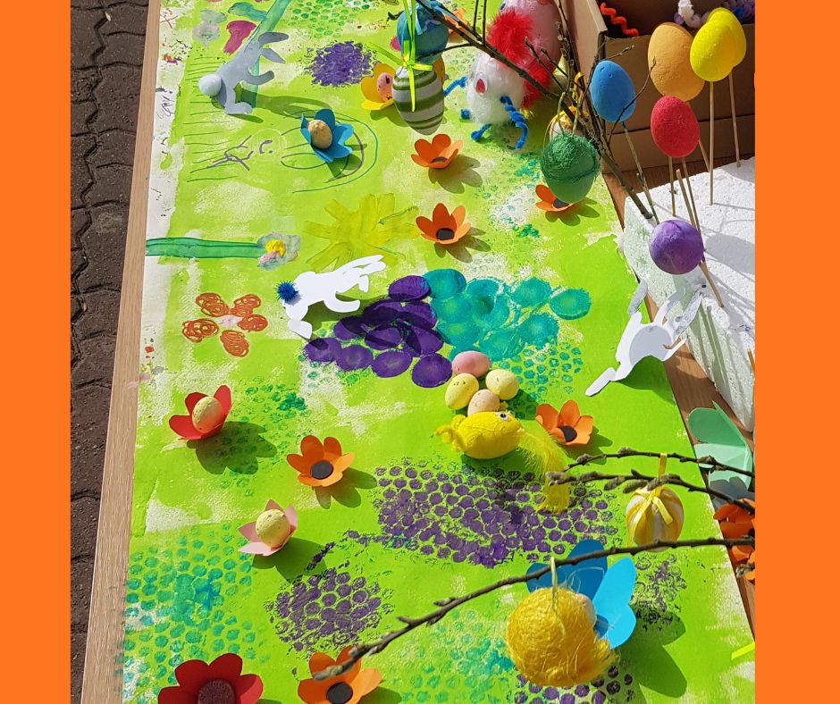 Obraz stworzony przez dzieci przedstawiający fantazyjną kolorową łąkę z elementami 3D w postaci papierowych kwiatów, zajączków i pisanek
