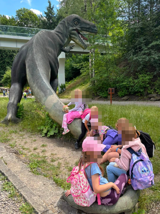 dzieci siedzące na ogonie ogromnej makiety dinozaura