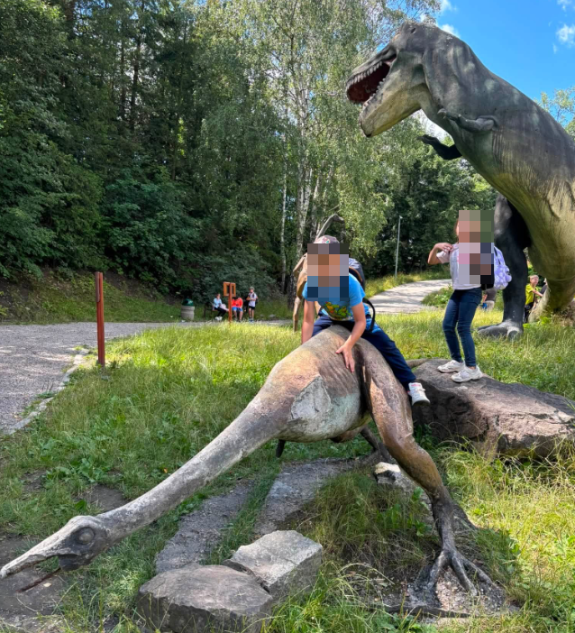 dzieci siedzące na makiecie dinozaura